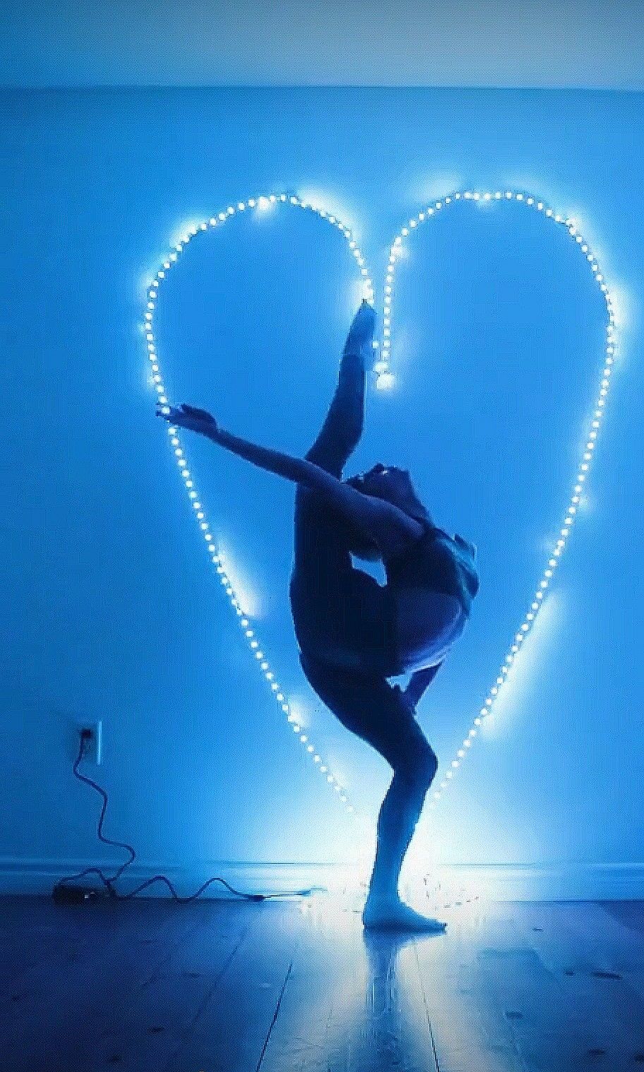 A person is doing yoga in front of an illuminated heart - Gymnastics