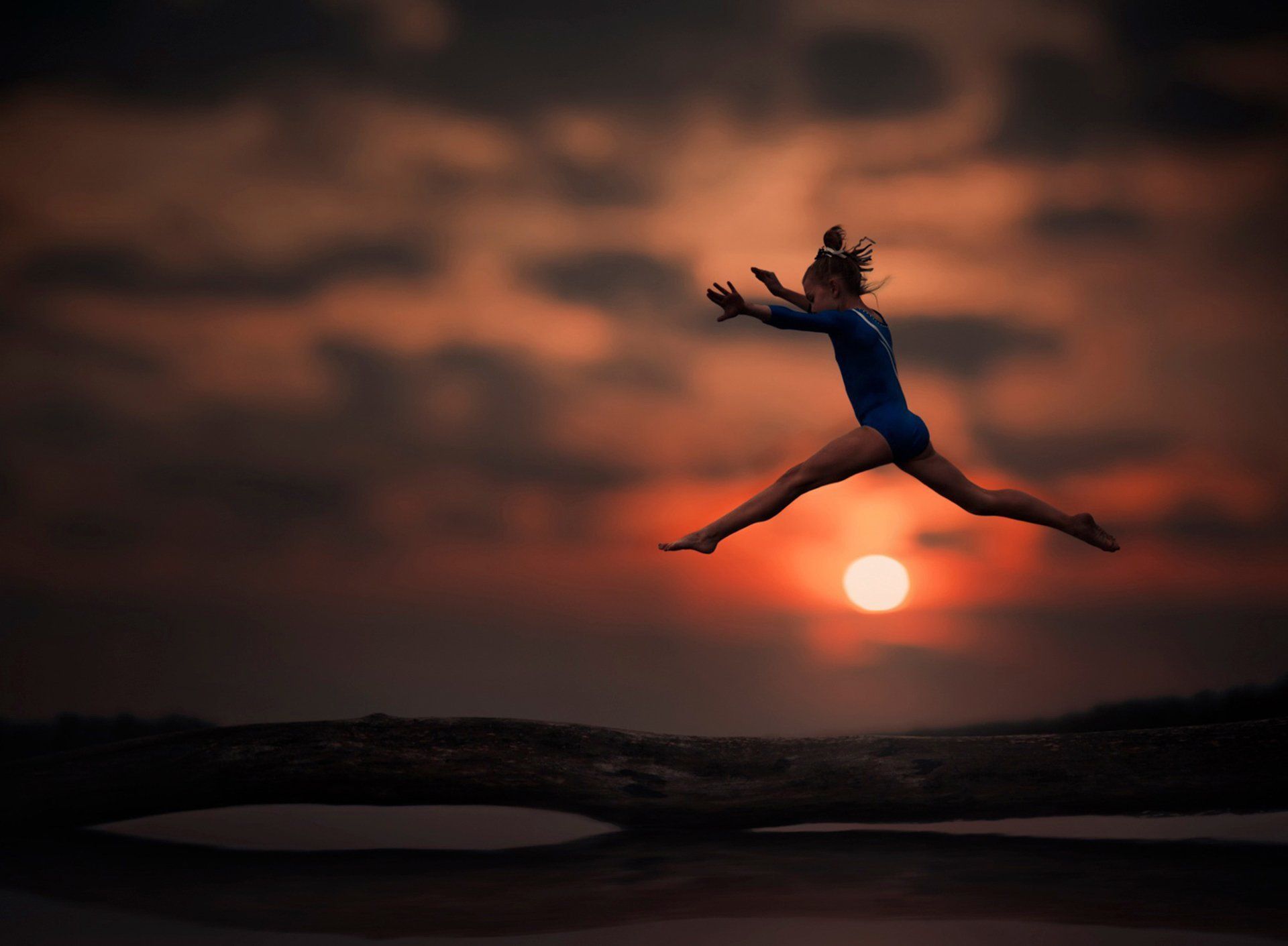 A woman in blue jumps over the water - Gymnastics