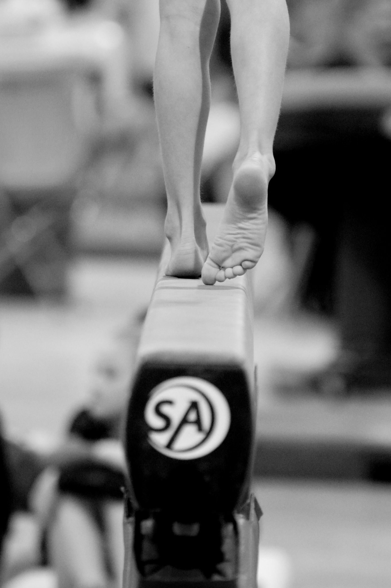 A gymnast's feet balance on the narrow edge of a balance beam. - Gymnastics