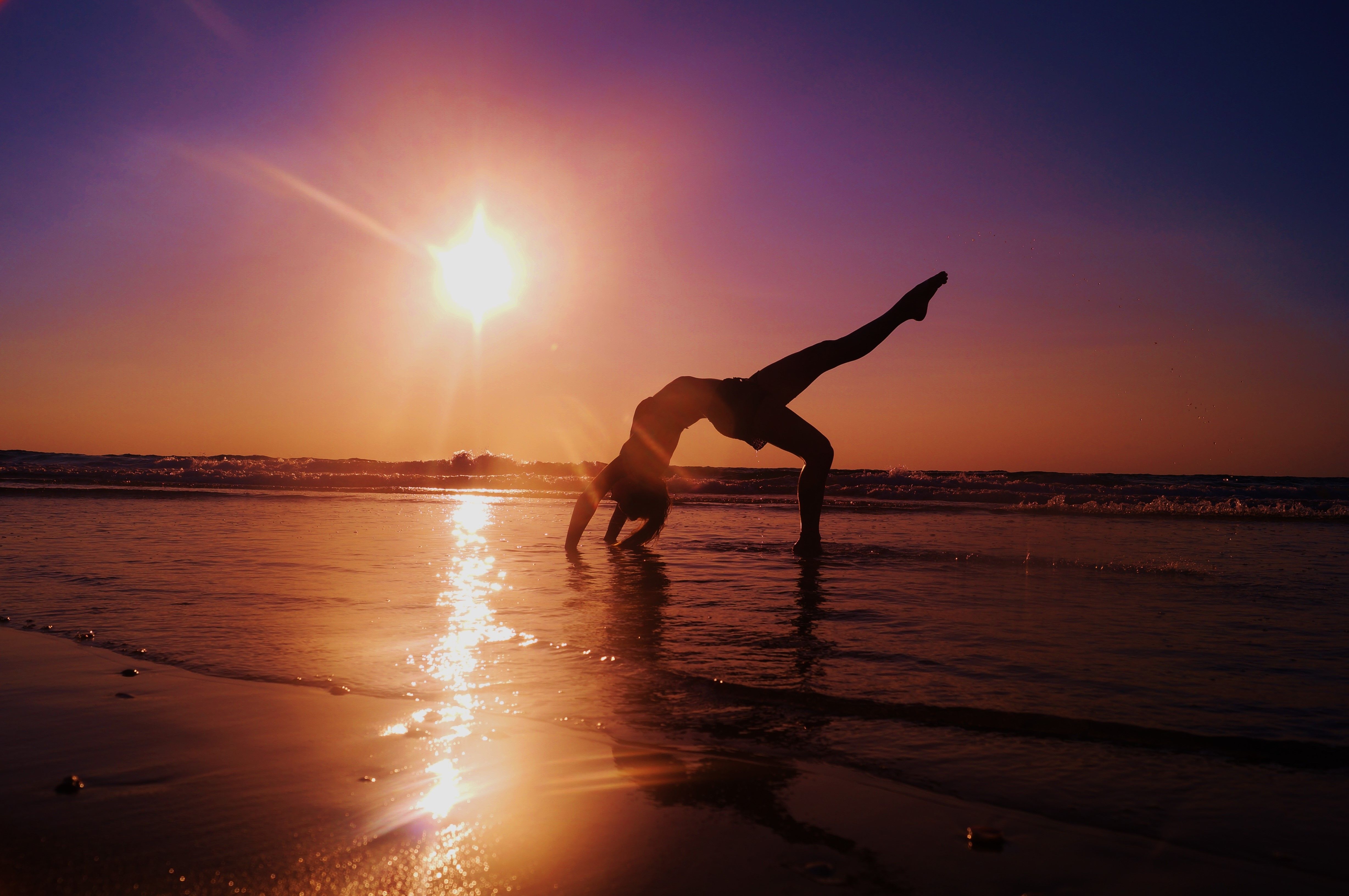 A person doing yoga on the beach at sunset - Gymnastics