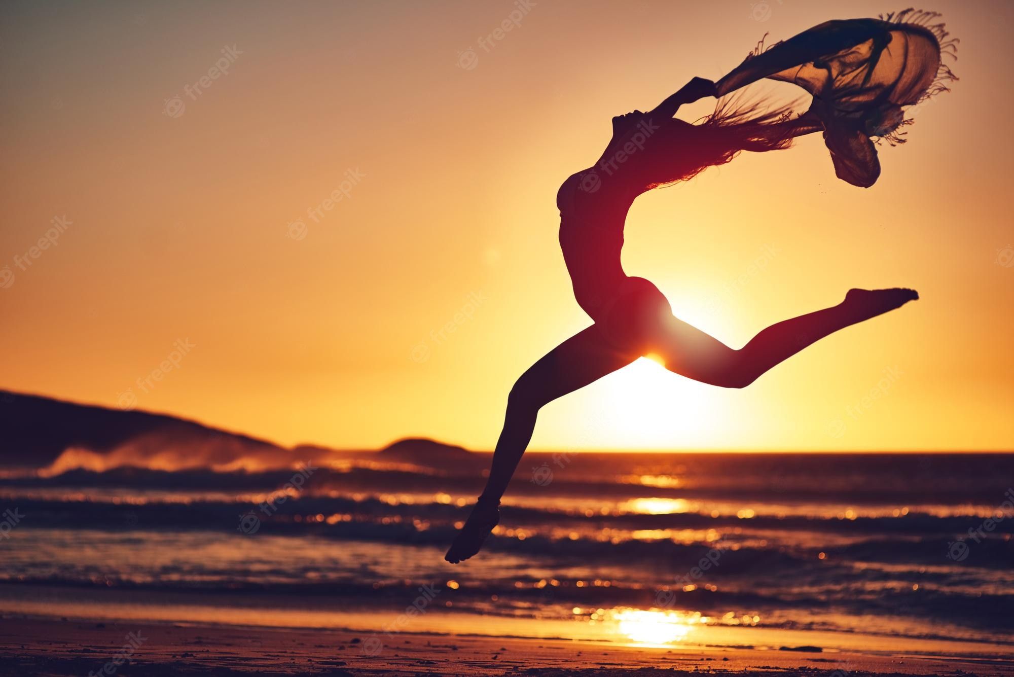 A woman is jumping in the air at sunset - Gymnastics