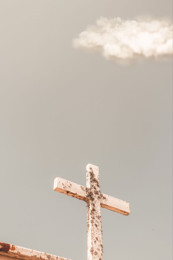 A cross on a church roof with a cloud in the sky - Cross