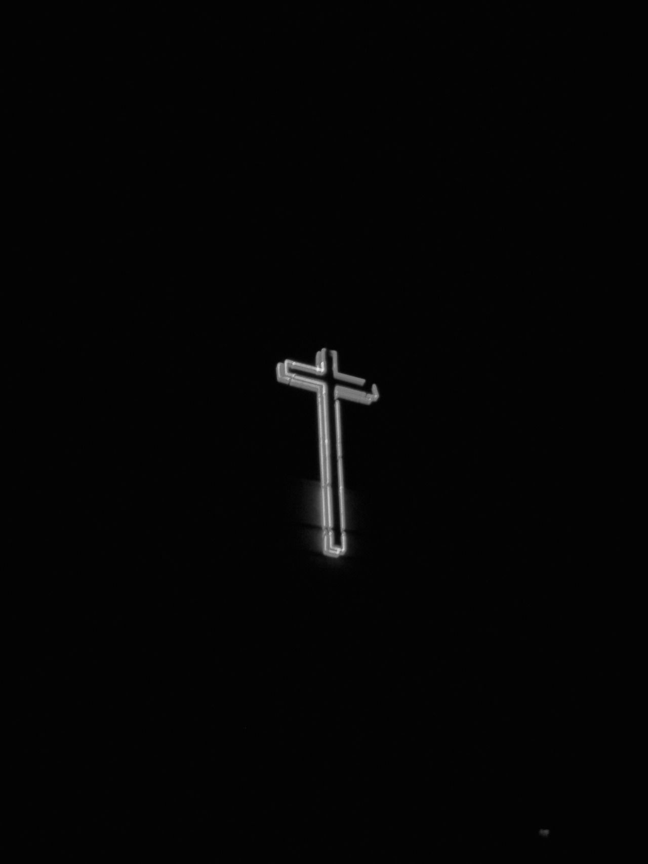 A black and white image of a cross against a black background. The cross is made up of white lines and appears to be glowing. The image is set in a square format. - Cross