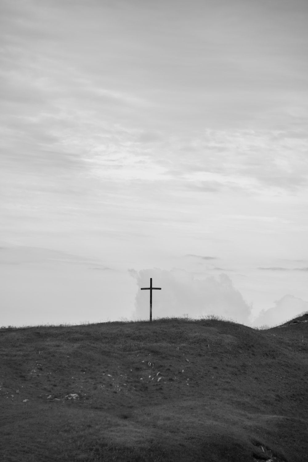 A cross on a hillside in black and white. - Cross