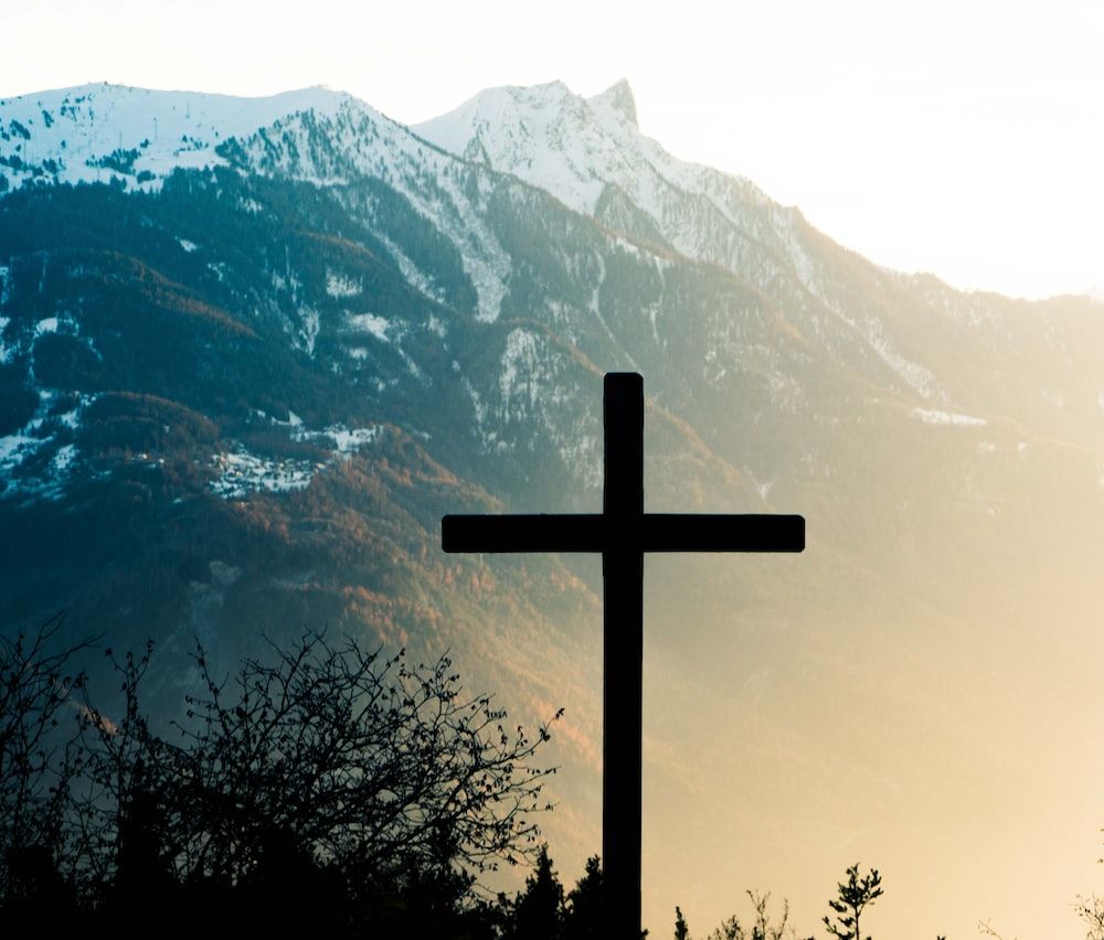 A cross in front of a mountain. - Cross