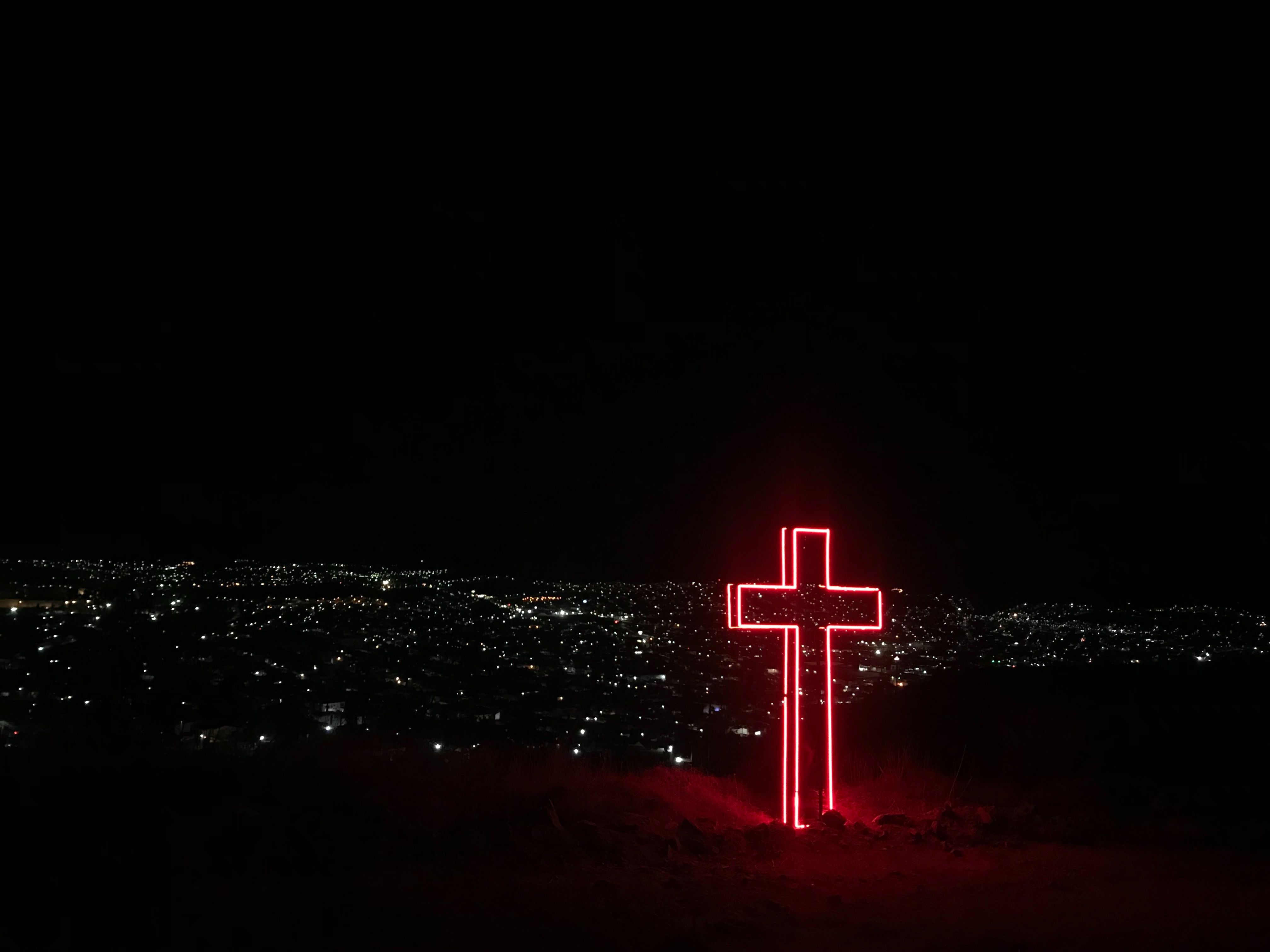 A red neon cross in the middle of a city at night. - Cross, Christian