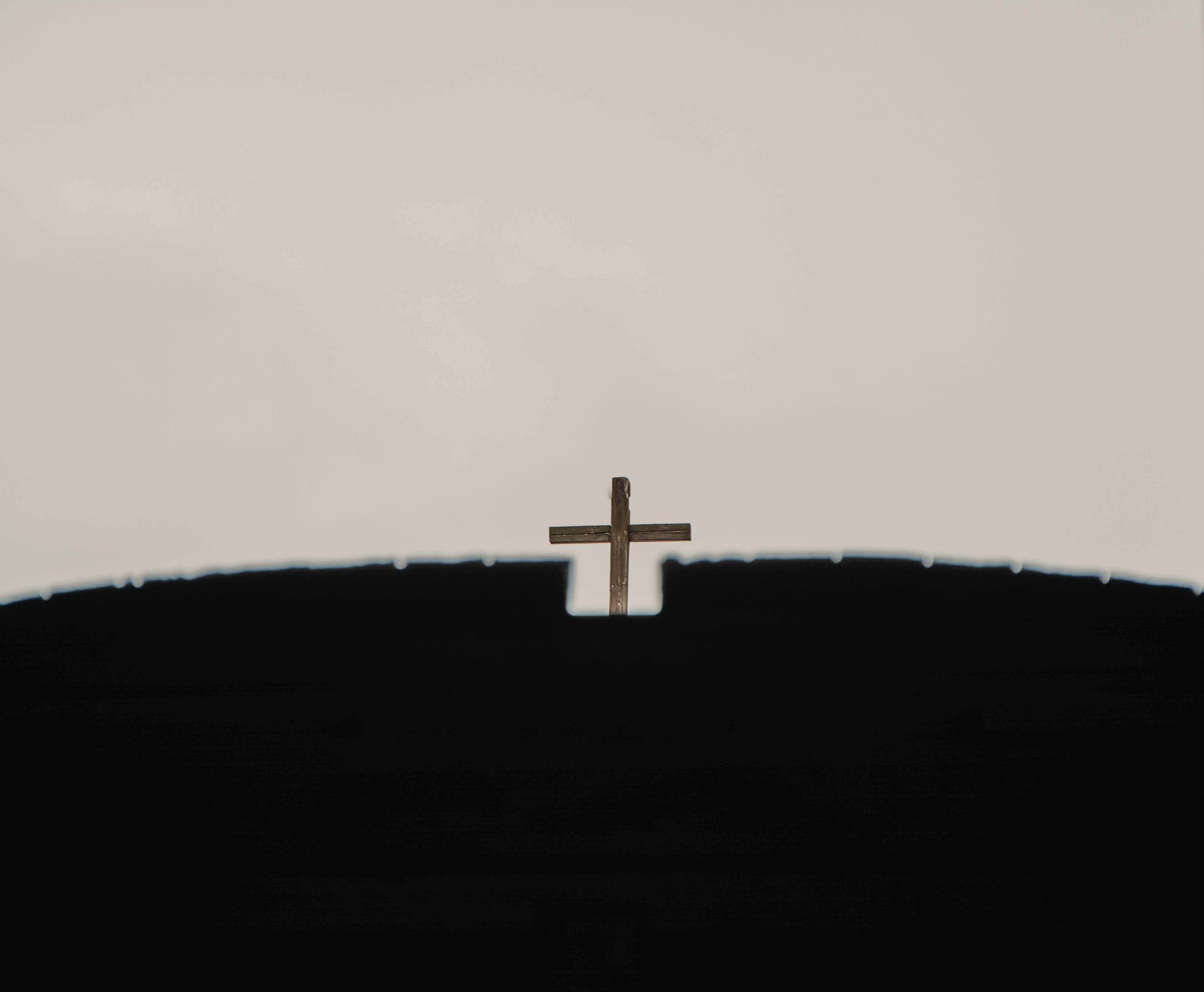 Christian cross under light sky on temple roof · Free