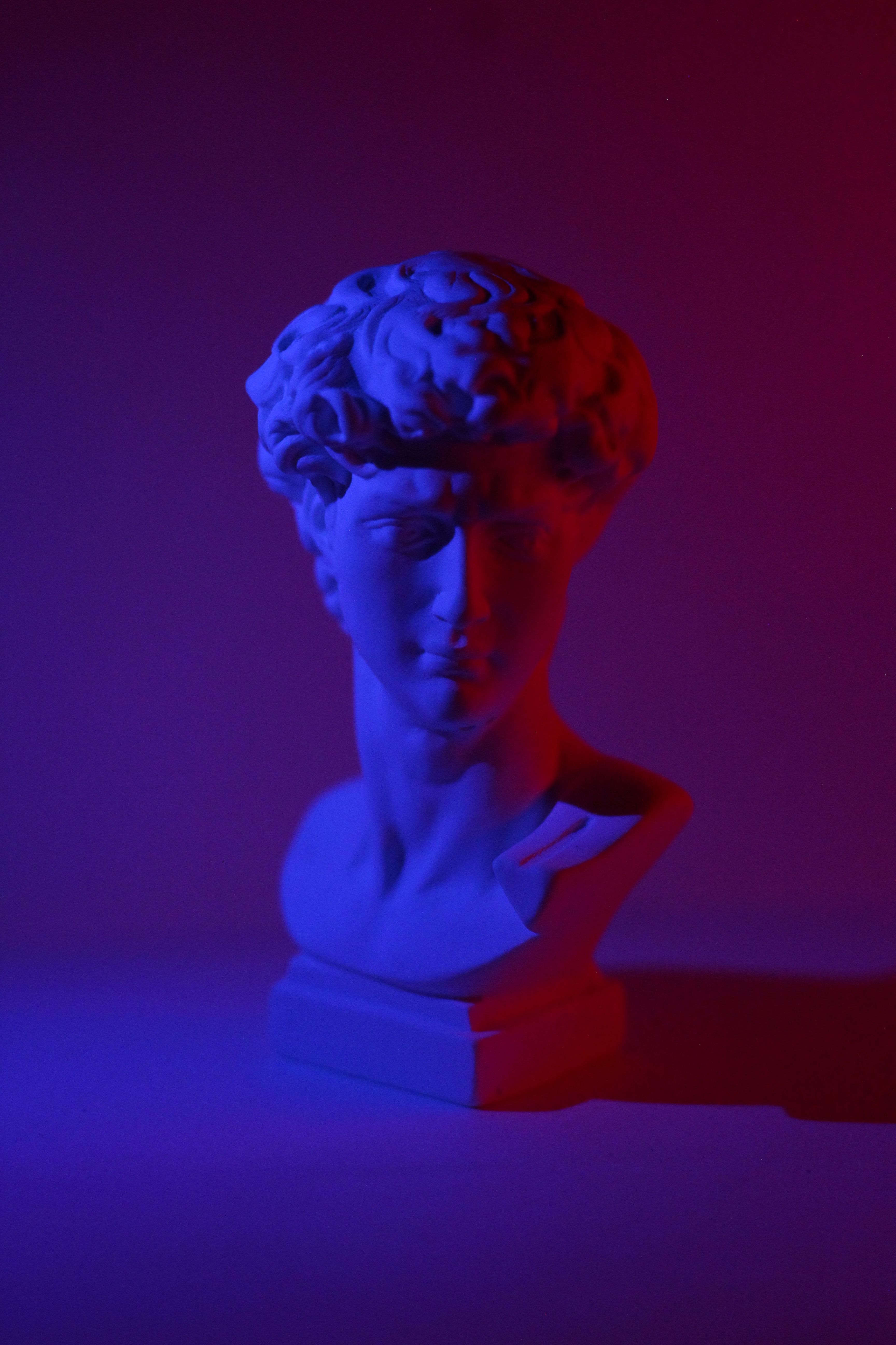 A sculpture of David's head, with a blue and red light shining on it. - Greek statue, statue