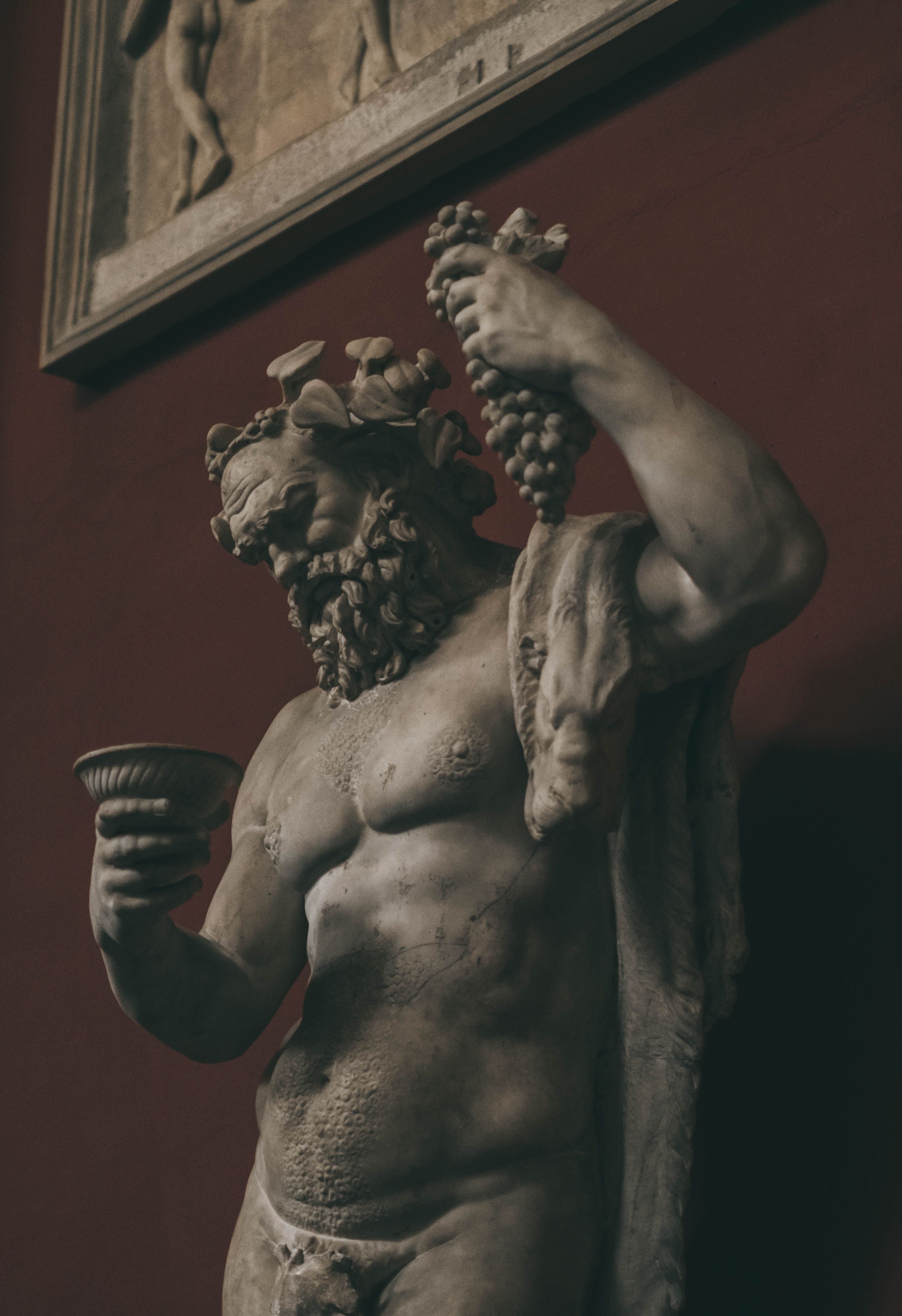 A statue of a man holding grapes and a bowl. - Greek statue, Greek mythology, statue