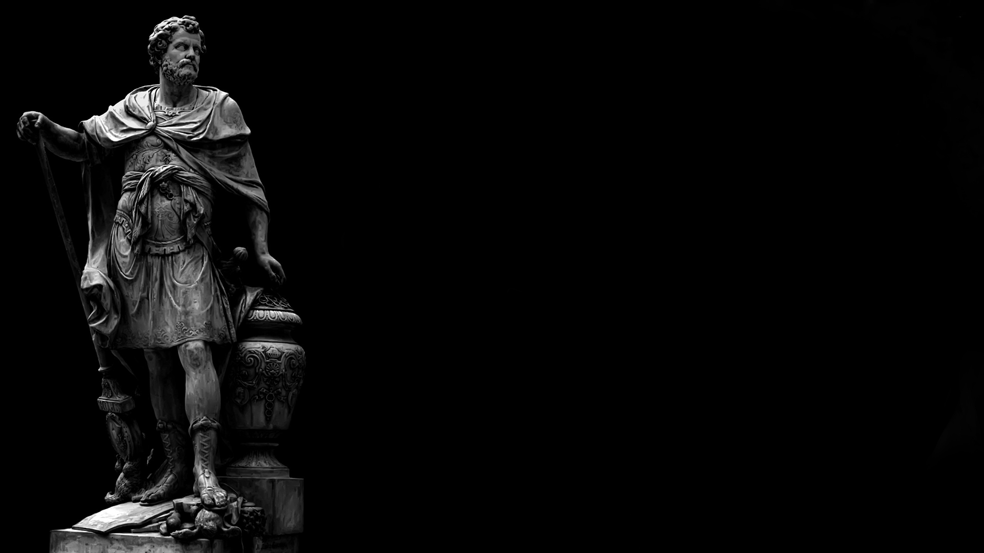 A black and white photo of a statue of a man with a beard and a cloak, holding a staff. - Greek statue