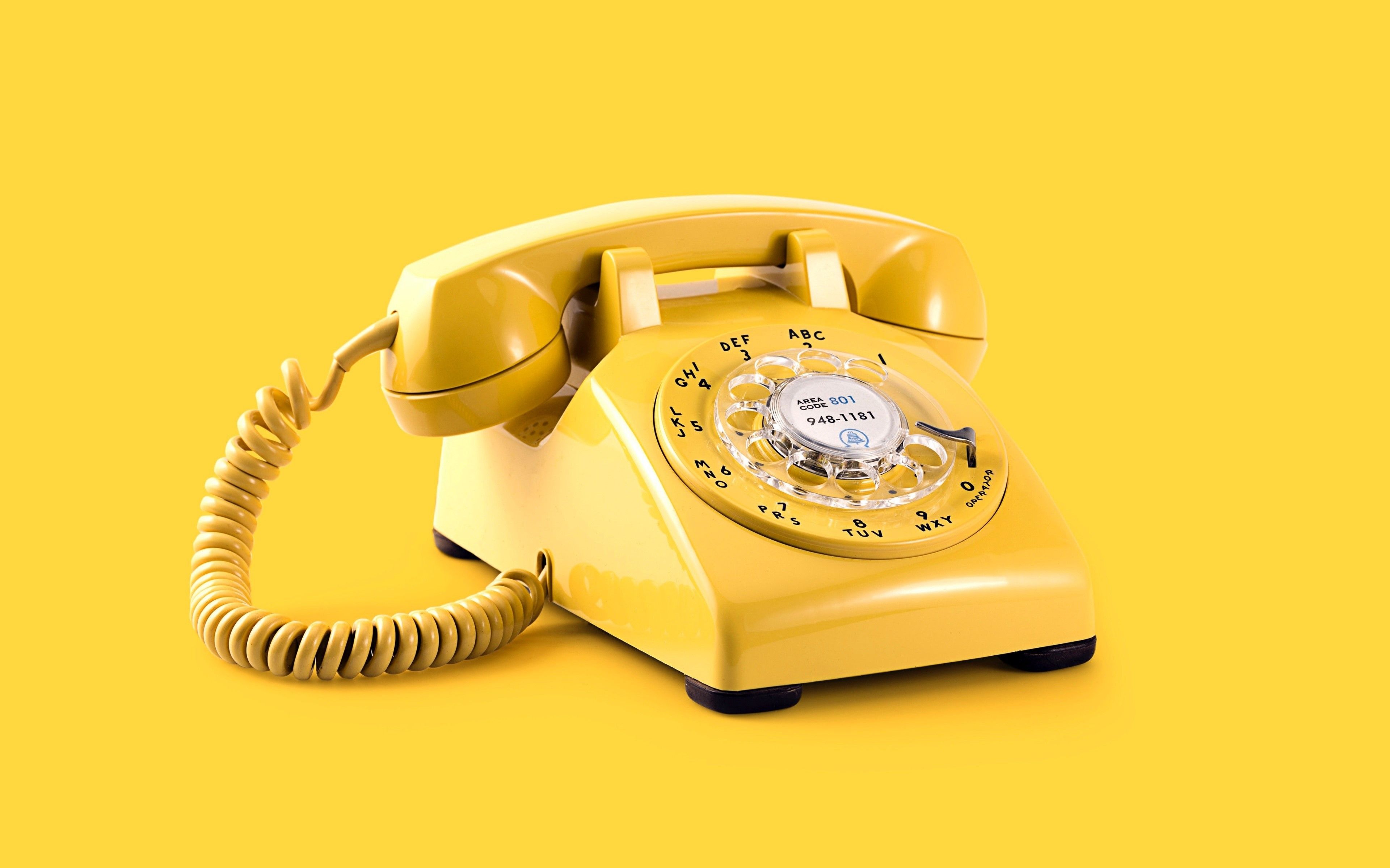 A yellow rotary phone on a yellow background - Yellow