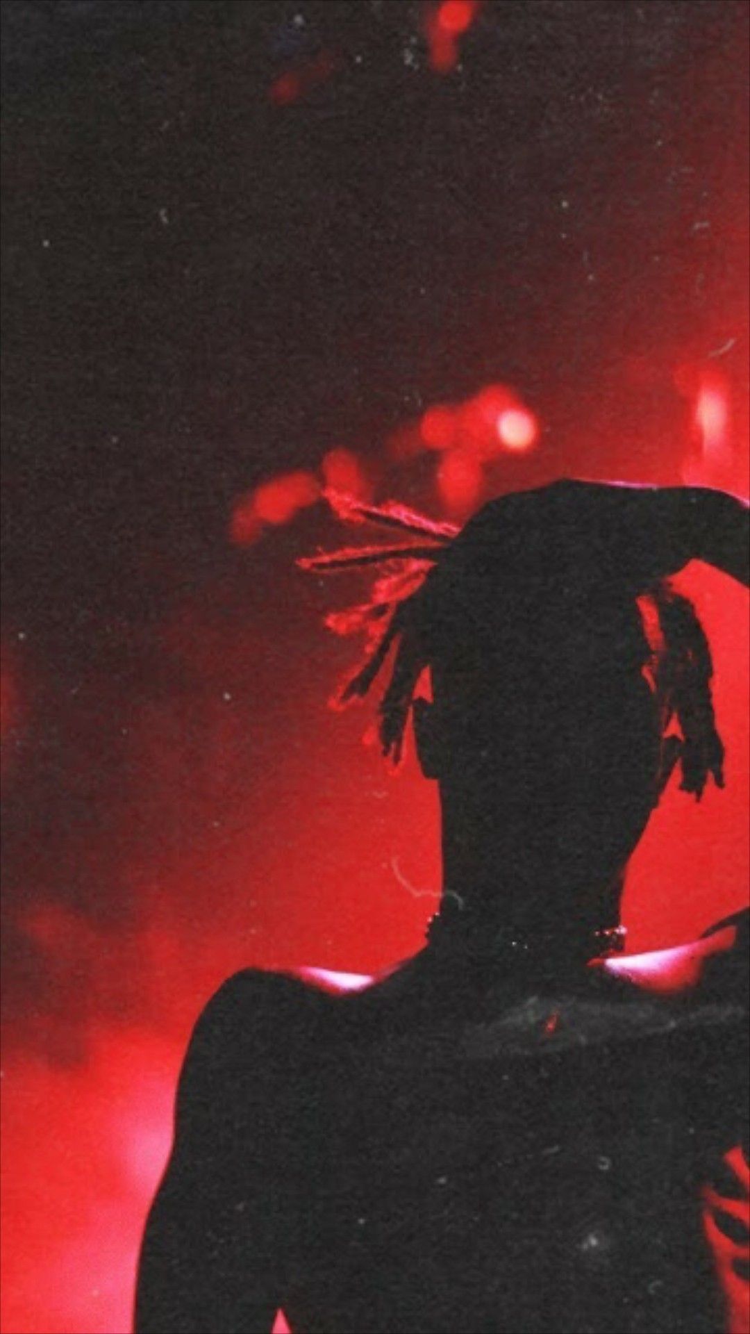 A person with long hair is standing in front of red lights - XXXTentacion