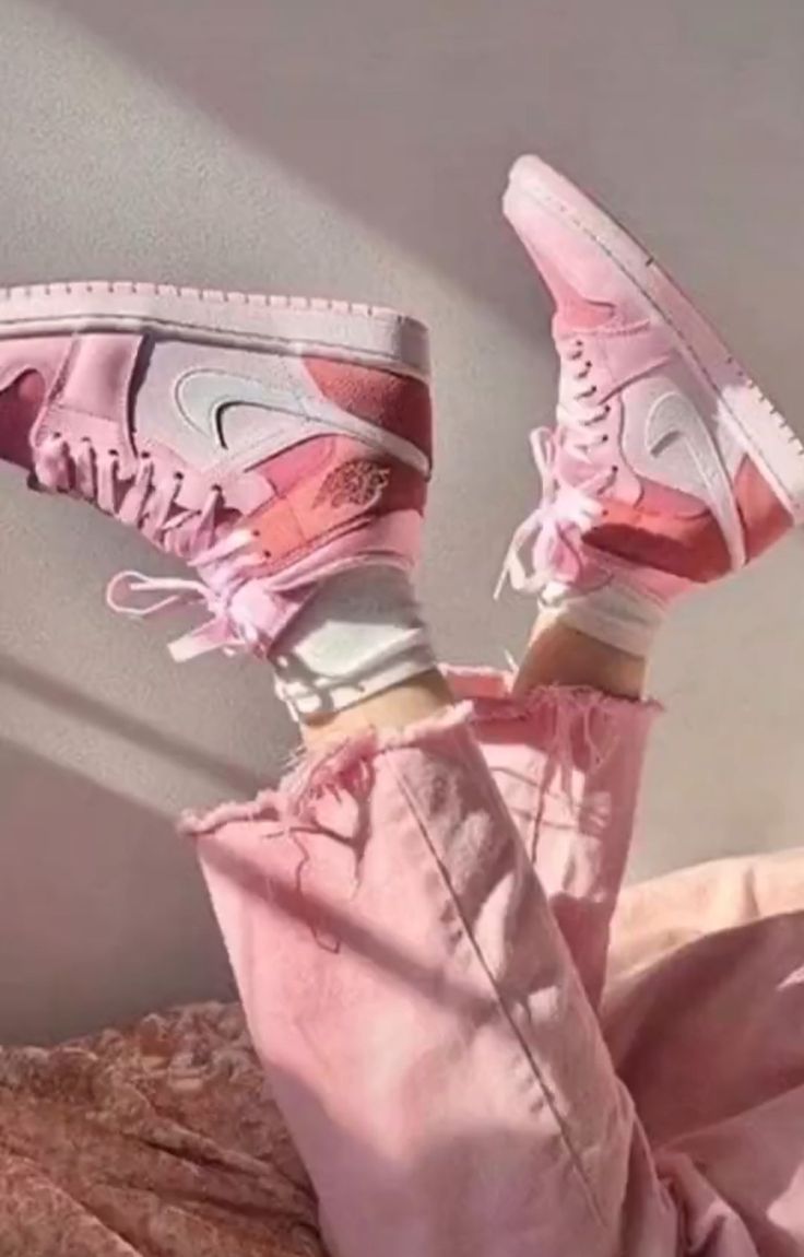 A person is wearing pink sneakers on the bed - Shoes