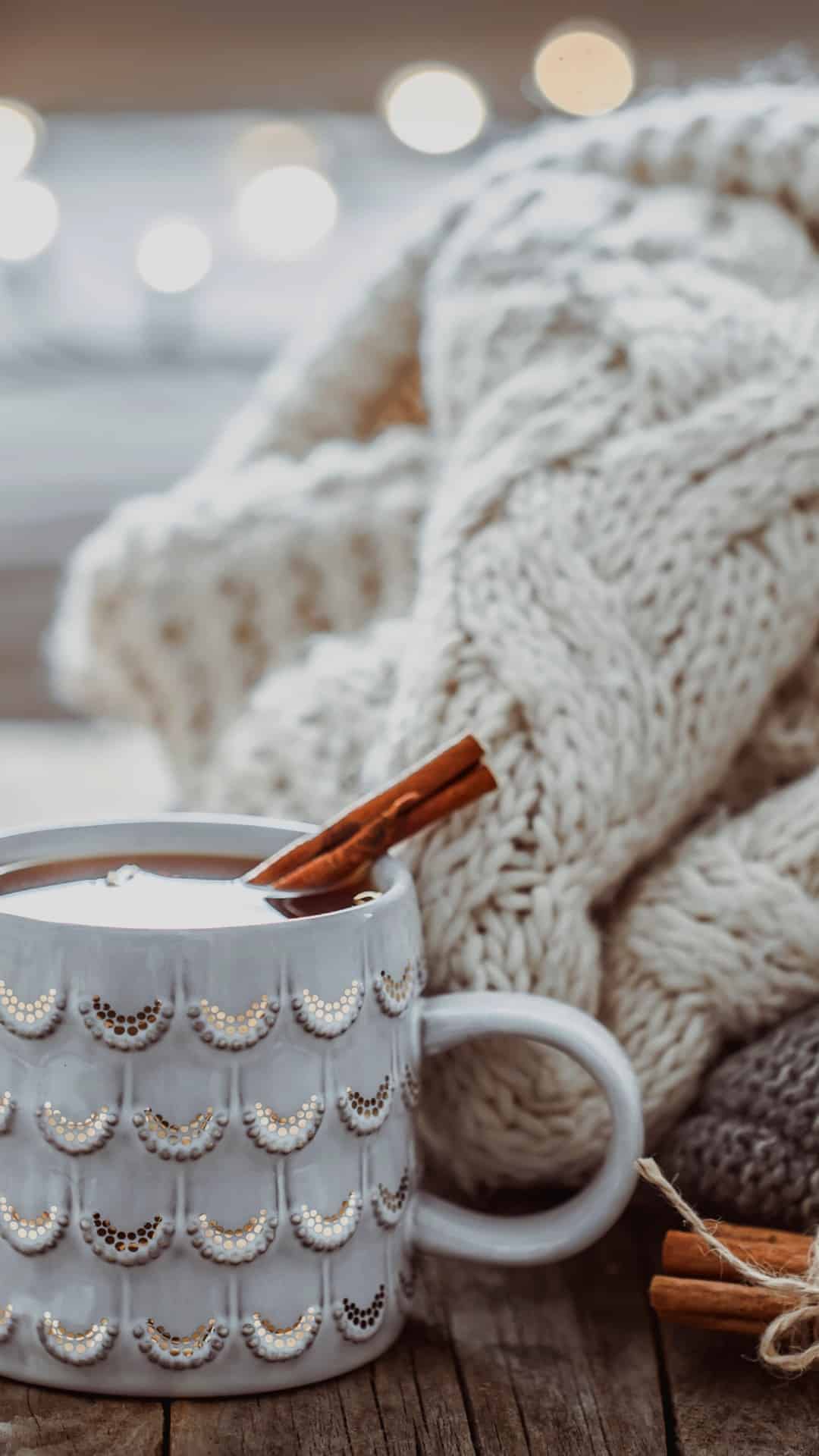 A white mug with a cozy white blanket in the background. - Cozy