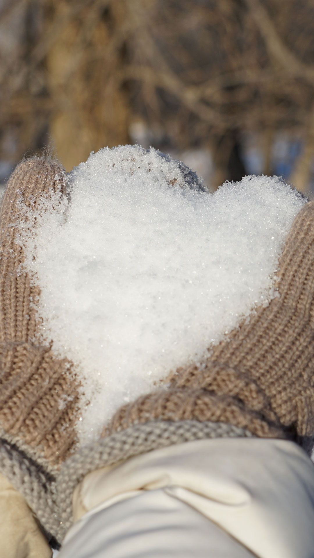 A person holding up some snow in the shape of heart - Cozy