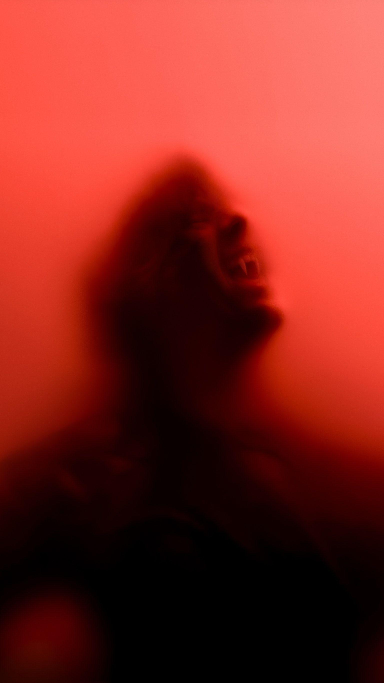 Red filtered image of a man with his eyes closed and mouth open, looking up. - Blood