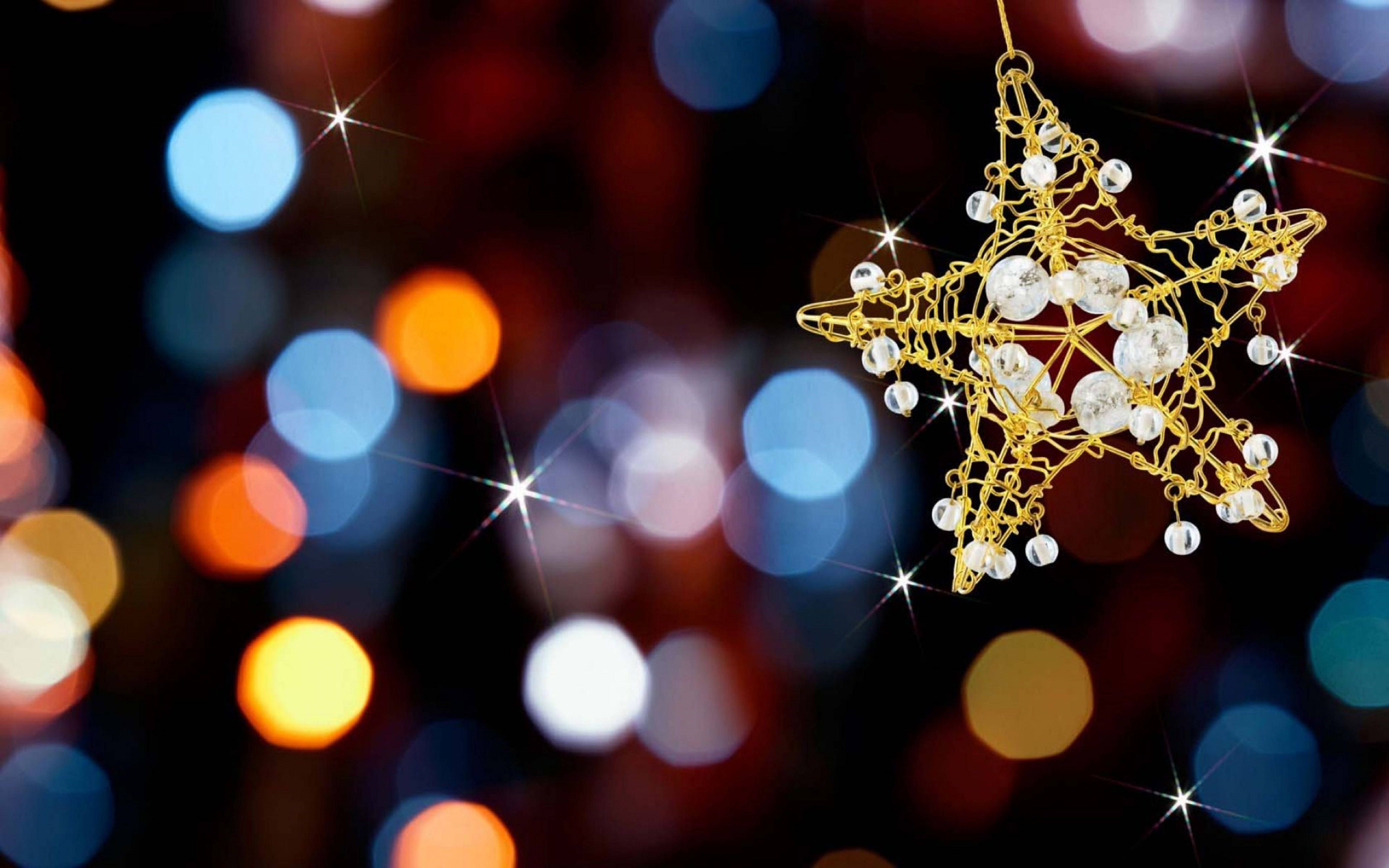 A golden star ornament with small white beads hanging from a gold string. - New Year