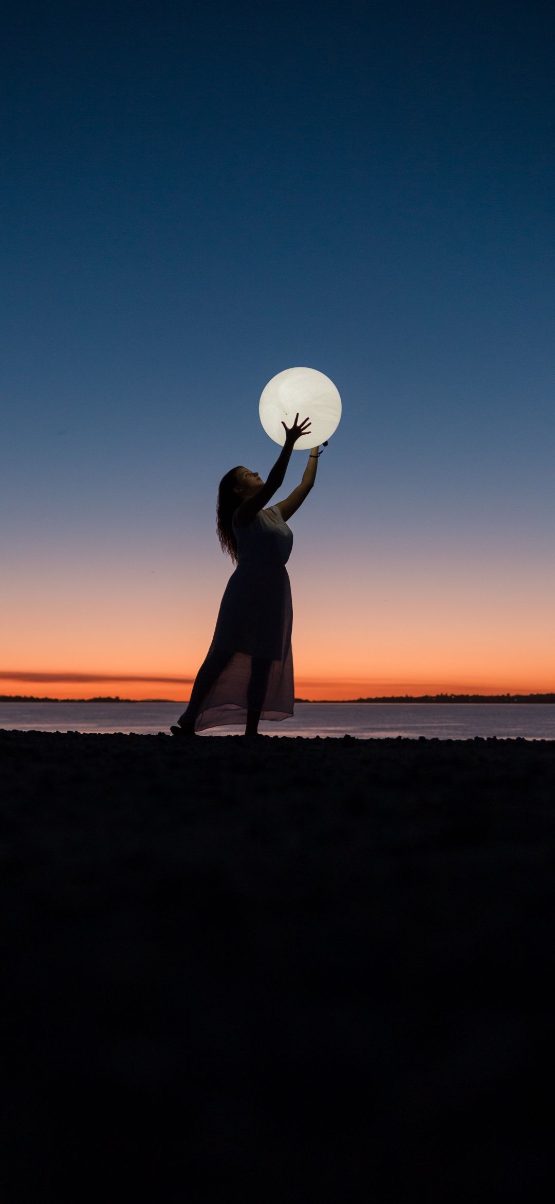 IPhone wallpaper of a woman holding the moon at the beach during sunset - Photography