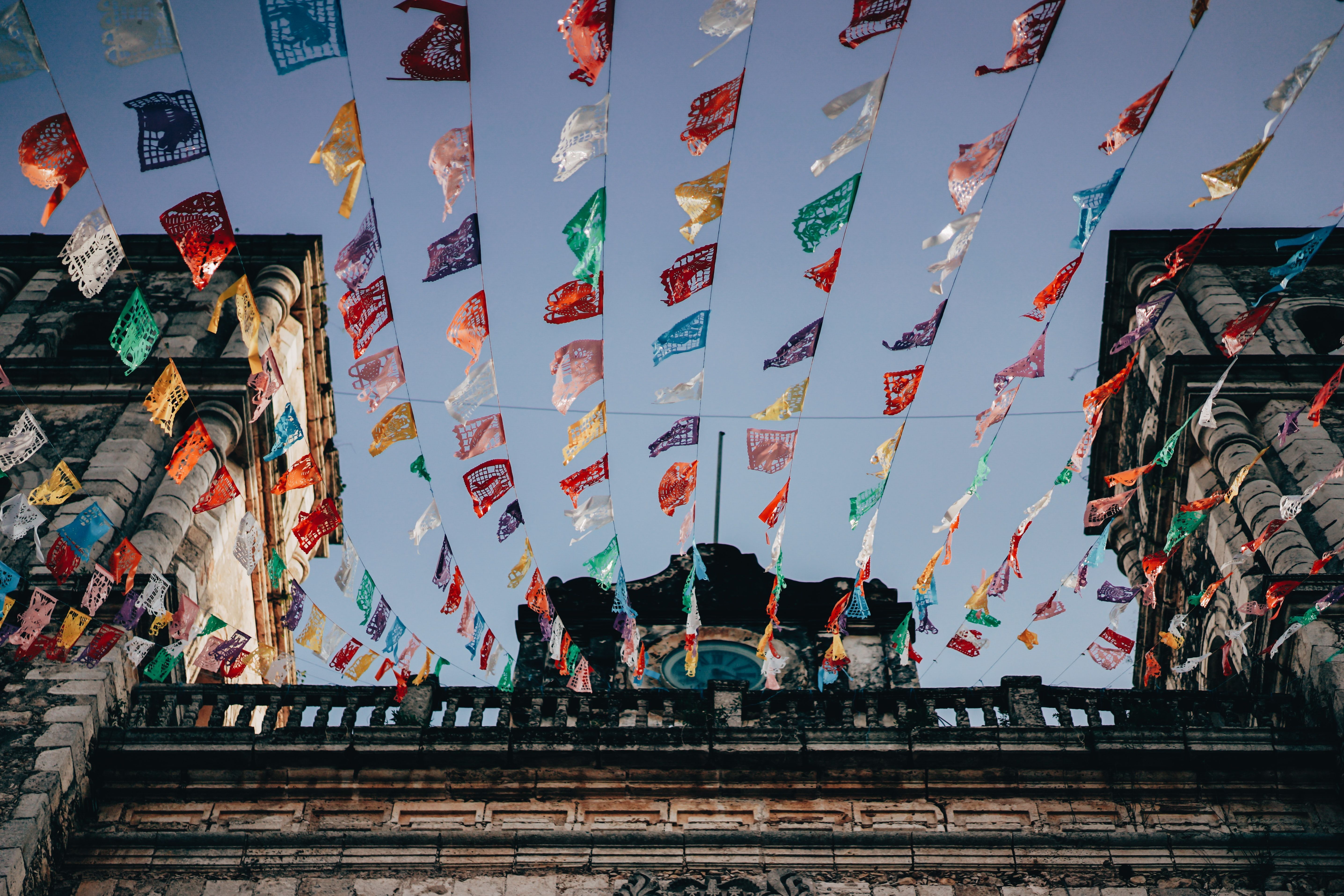 A low angle shot of a building with colorful flags hanging from the ceiling. - Mexico