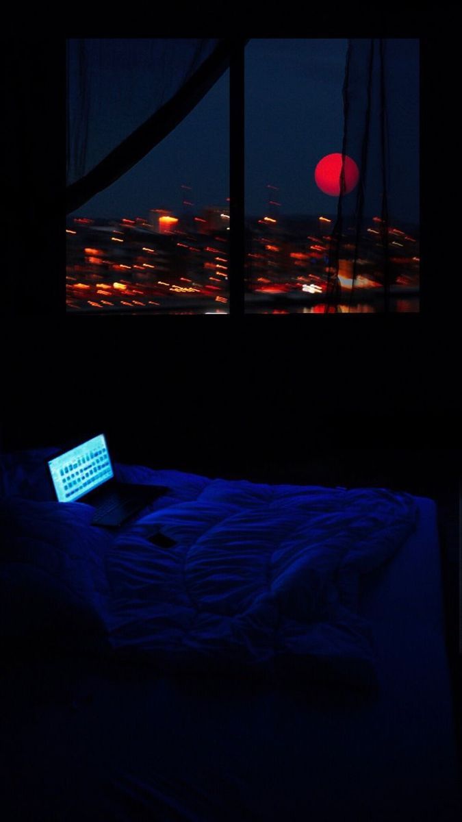 Laptop on a bed with a city view at night - Night