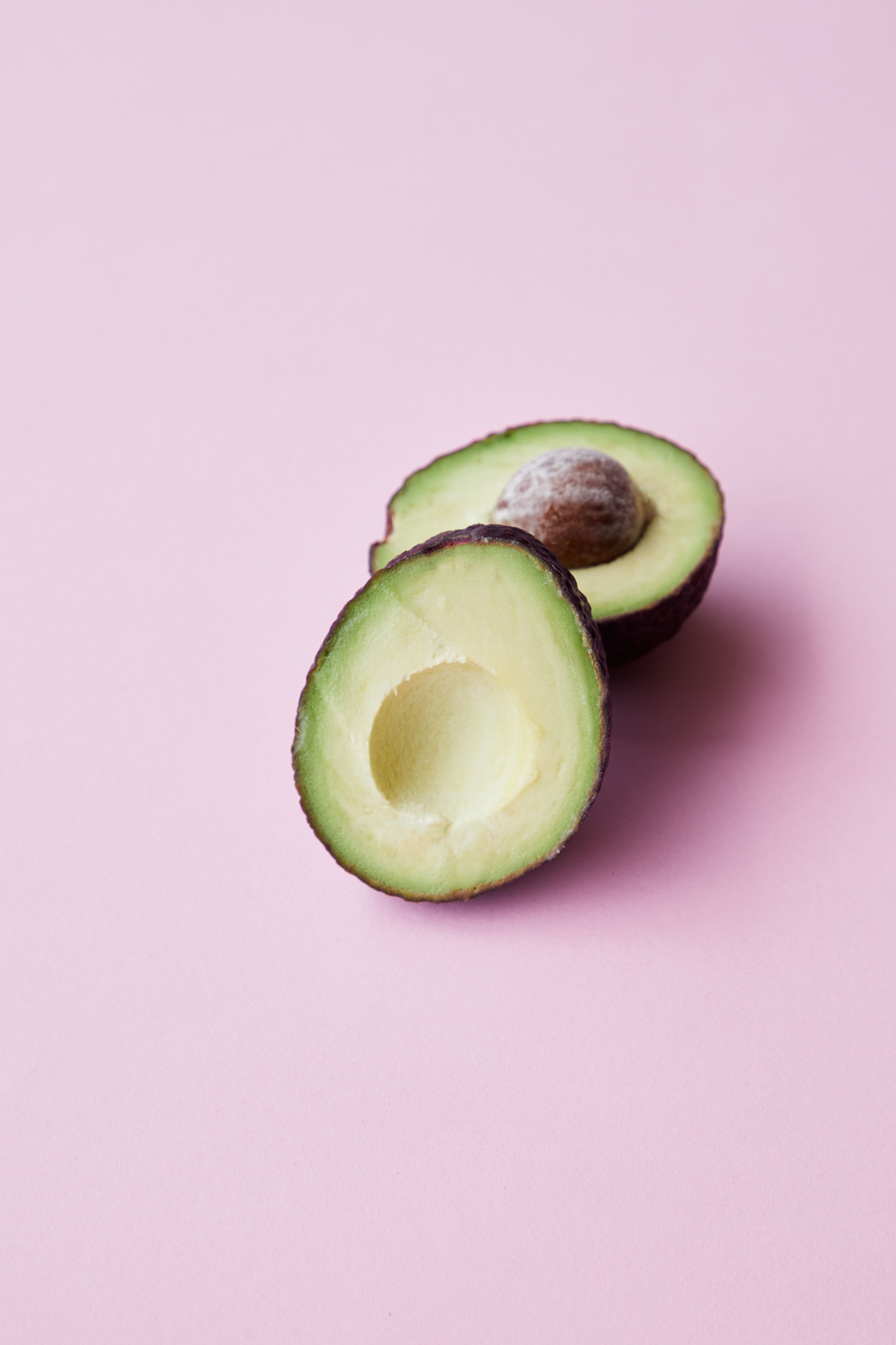 Halved ripe avocado placed on pink background · Free