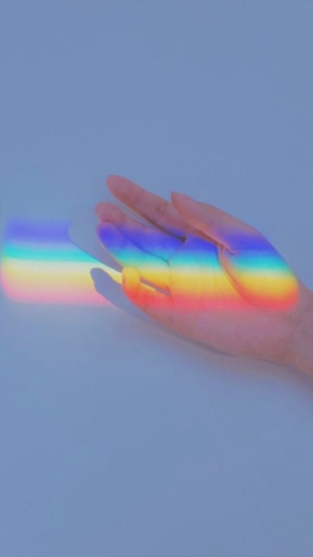 A hand holding up an image of rainbow light - Rainbows