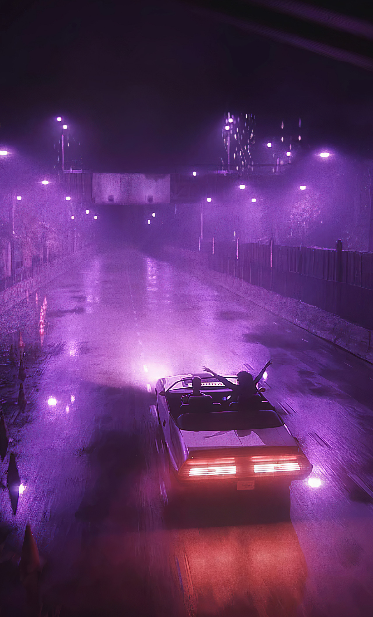 A car with a neon purple light on it drives down a wet road at night. - Night