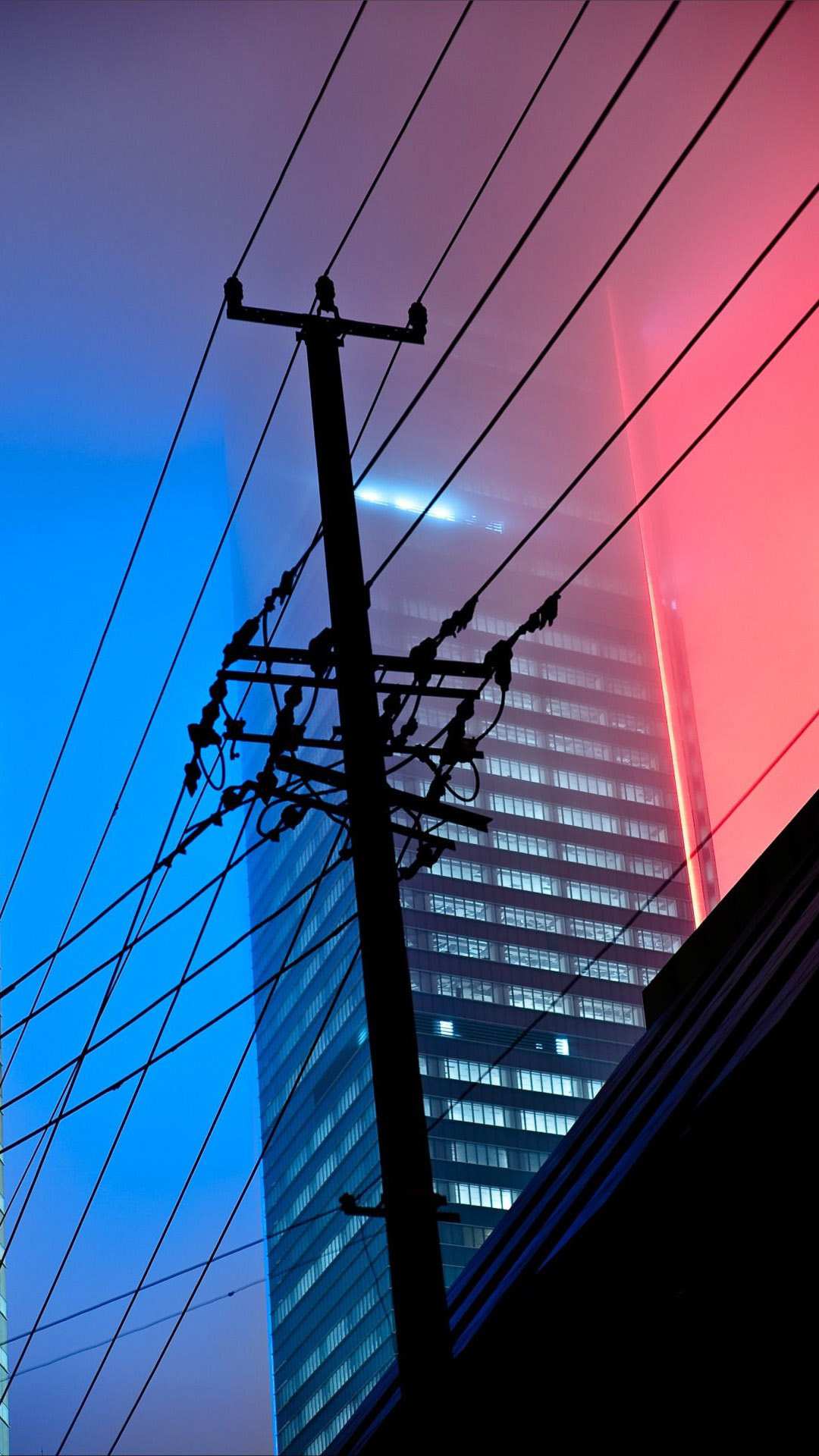 A red and blue lighted building in the distance - Night