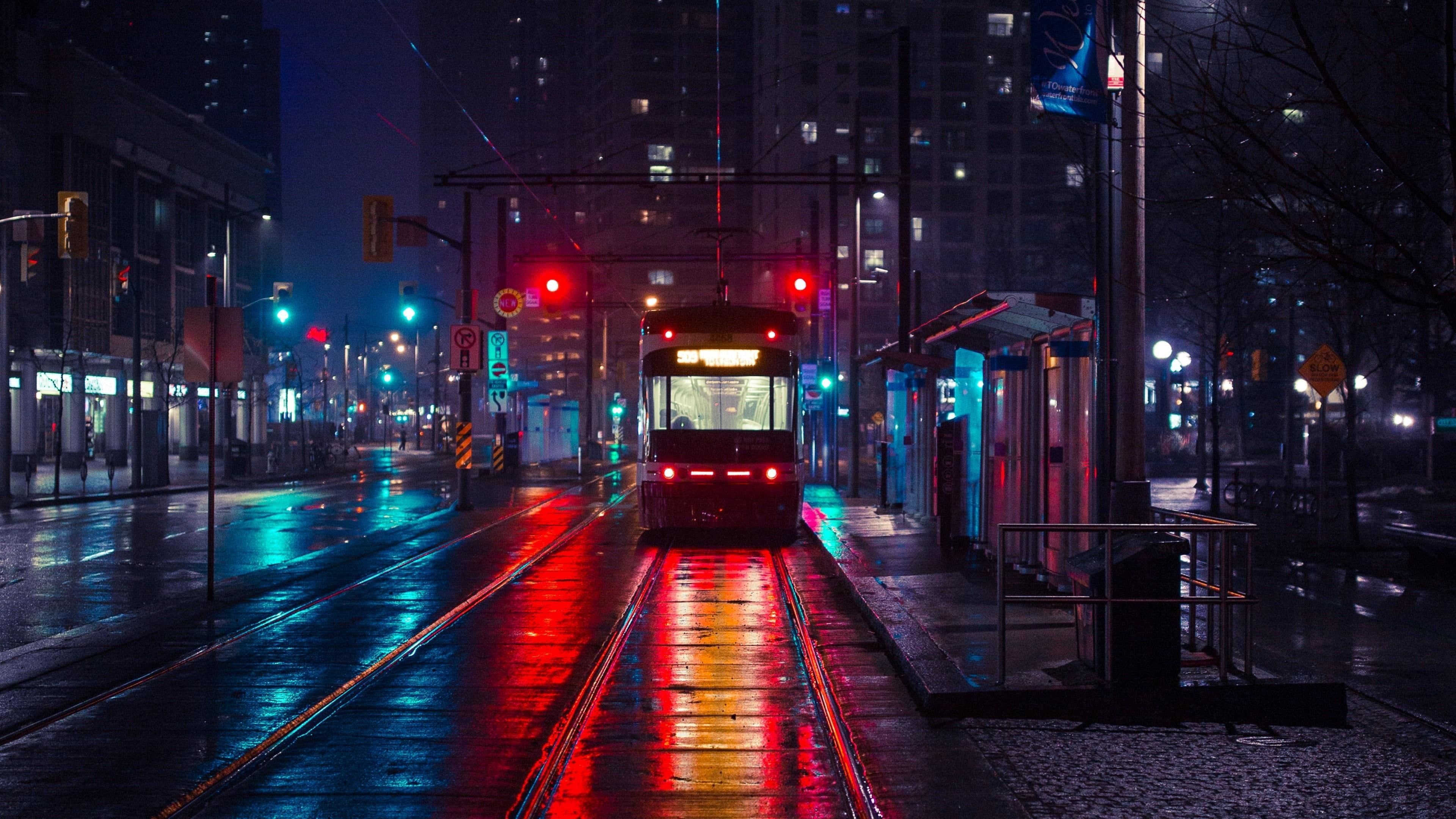 A train is coming down the tracks in the city at night. - Cityscape, night, city