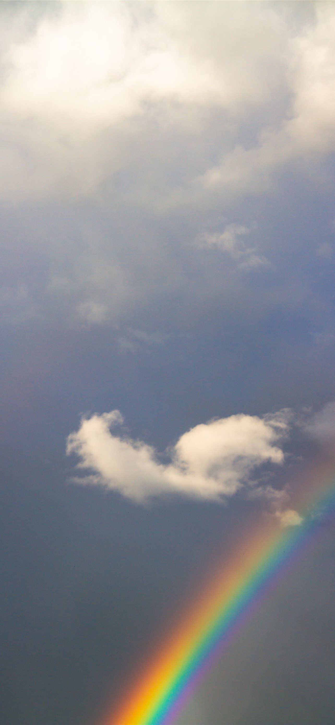 A rainbow in the sky with a cloud in the shape of a heart. - Rainbows