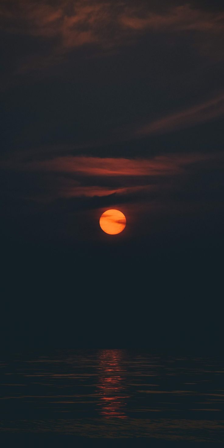 The sun is setting over the ocean. - Dark orange, night
