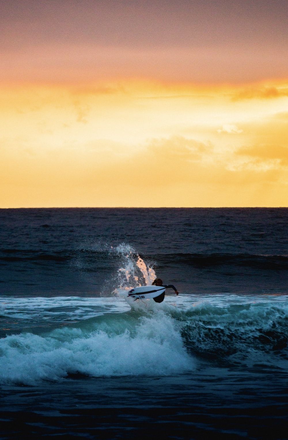 man surfing on sea waves during sunset photo