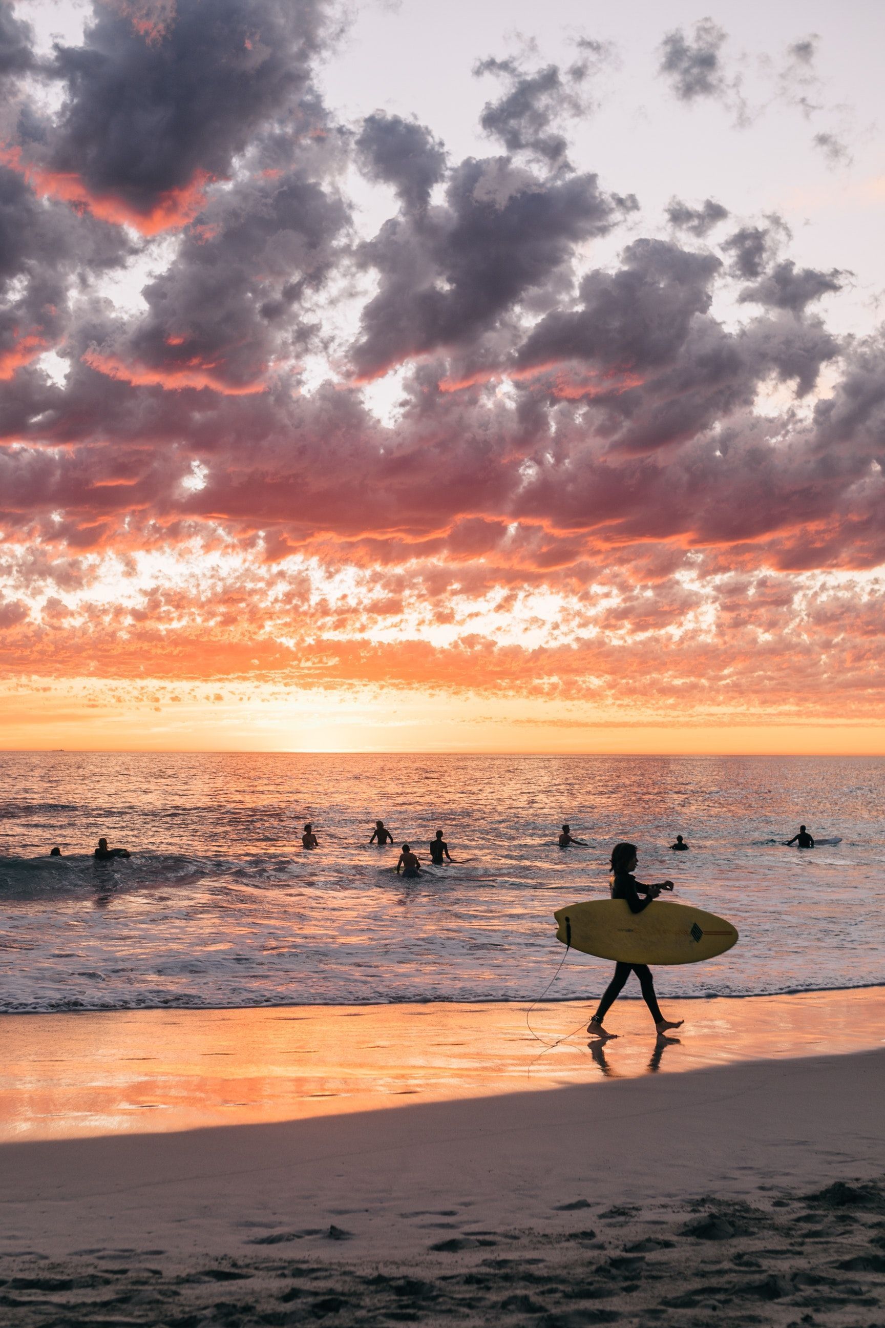 Unrecognizable people surfing at sundown on beach · Free