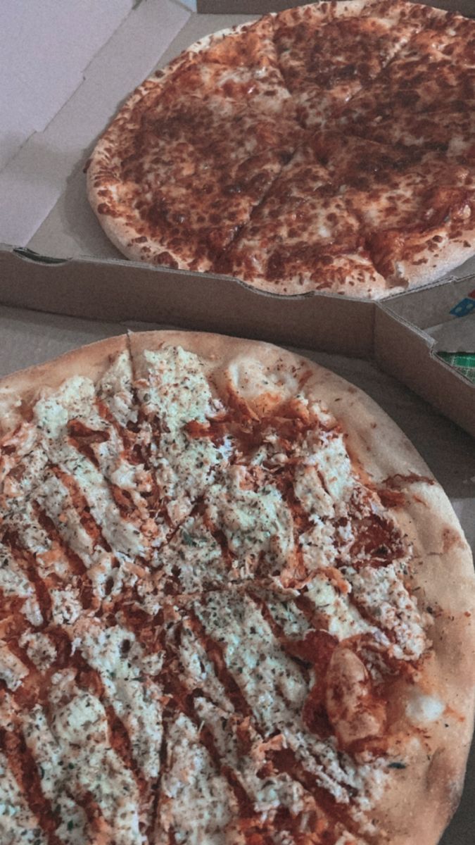 Two pizzas in boxes, one with white sauce and the other with red sauce. - Pizza