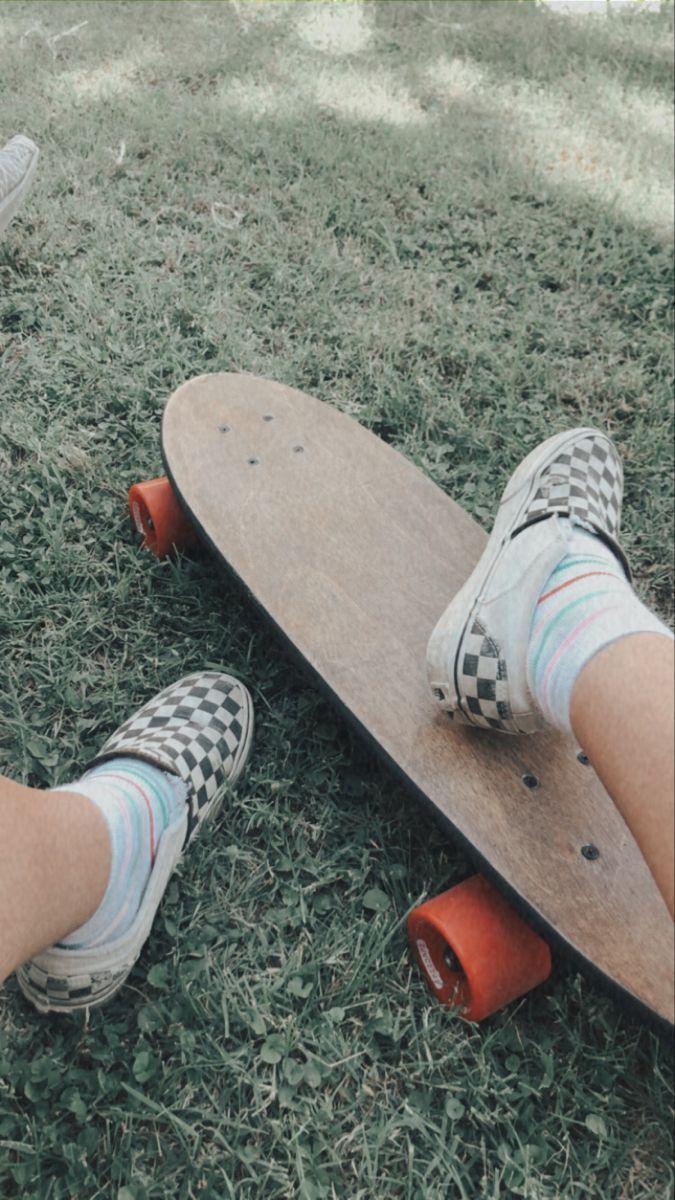 A person with checkered shoes on is sitting on a skateboard. - Skate, skater