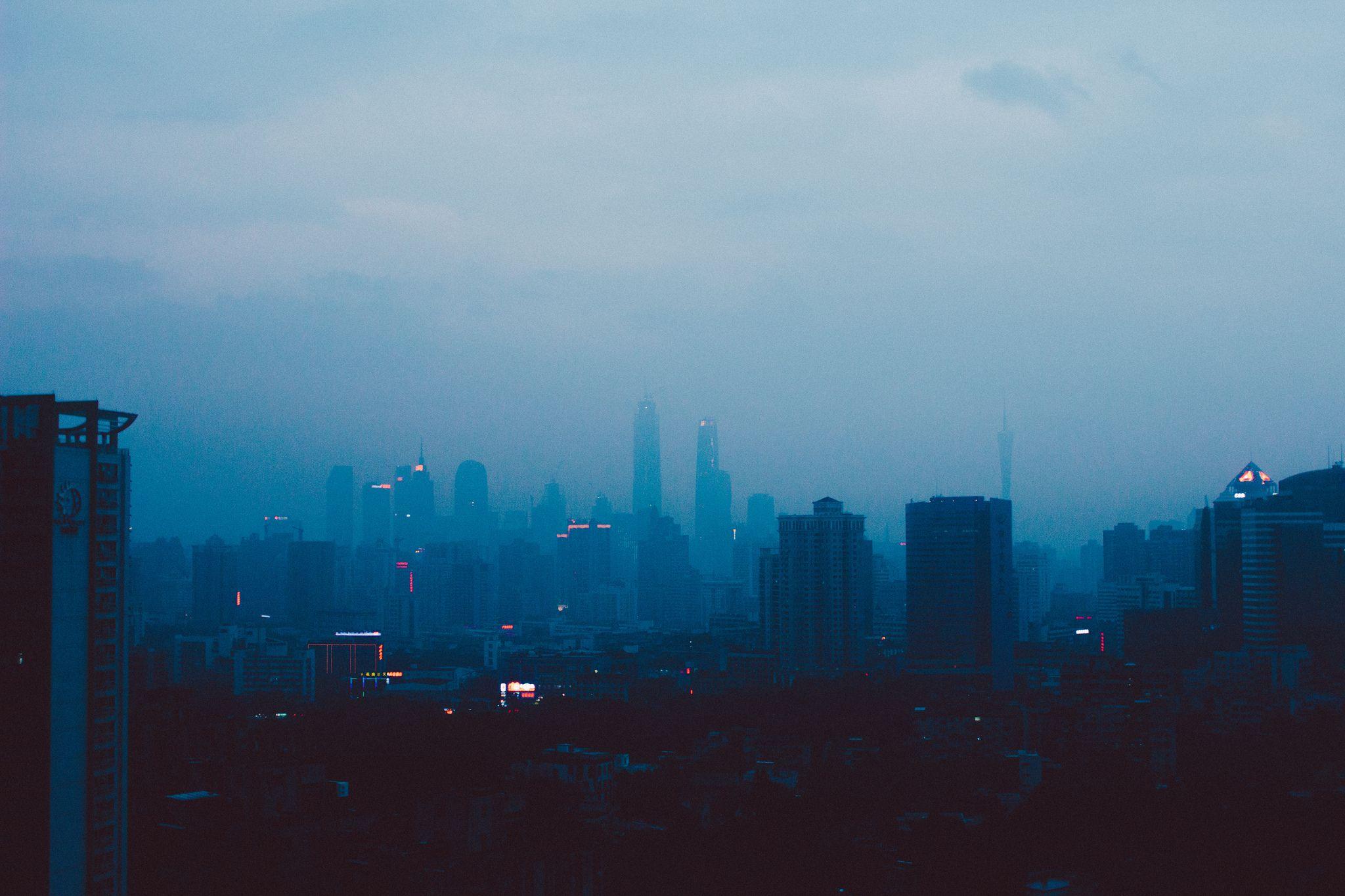 A hazy city skyline at dusk with a blue hue. - Lo fi