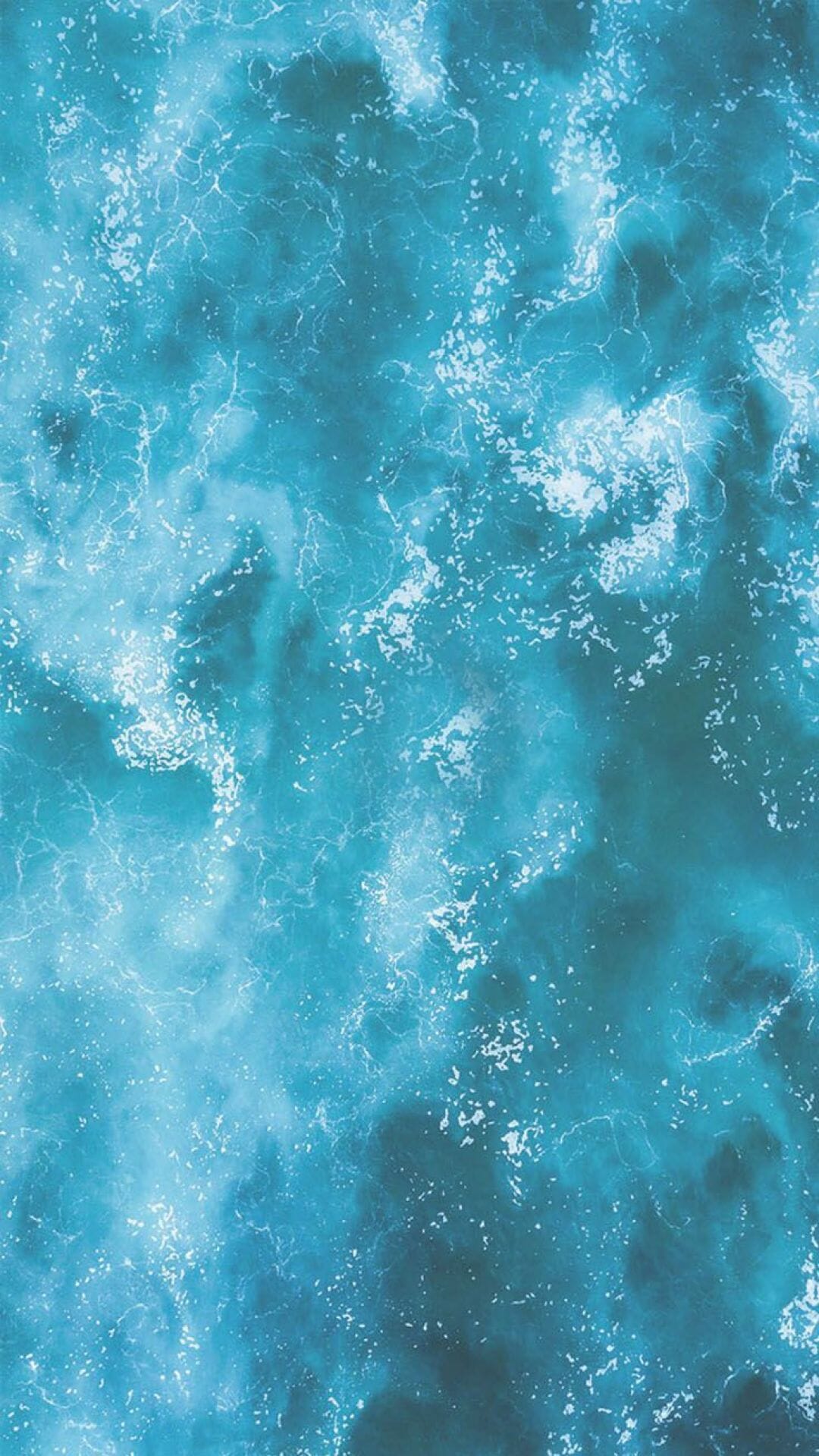 An aerial view of a blue ocean with waves - Teal, turquoise