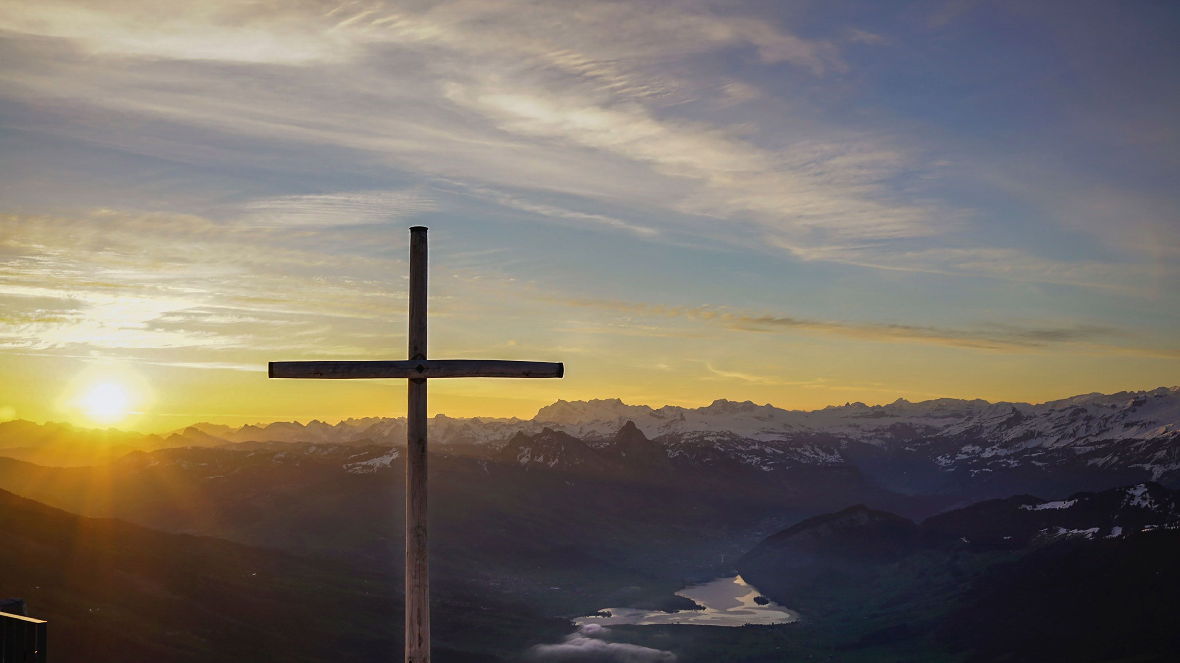 A cross in the foreground with a mountain range in the background. - Cross