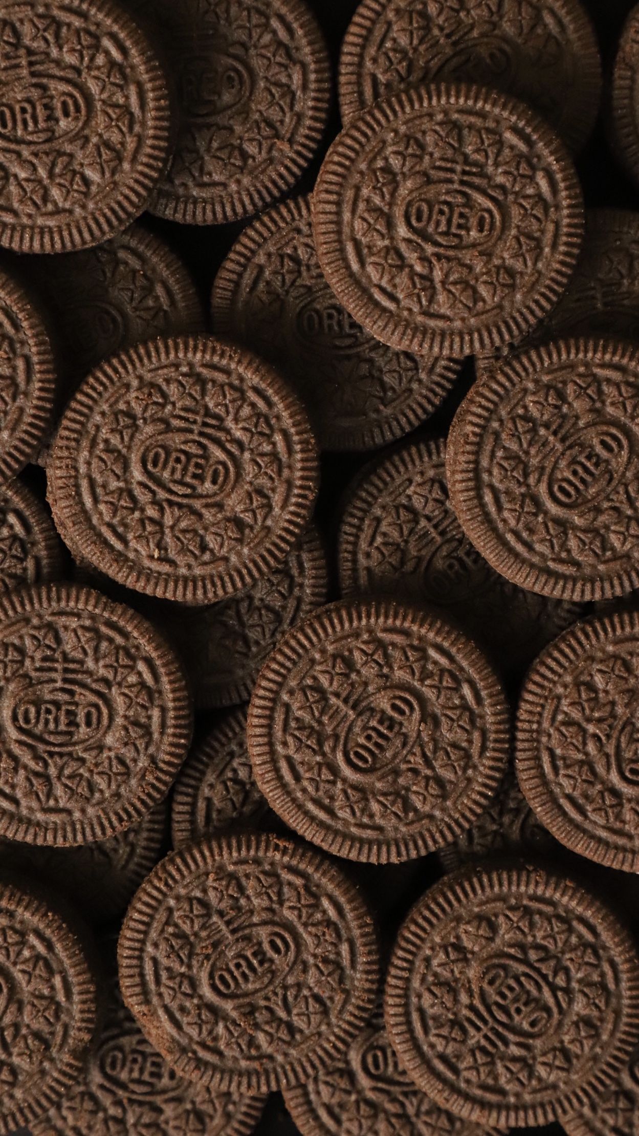 A pile of chocolate sandwich cookies with the word Oreo on them. - Oreo