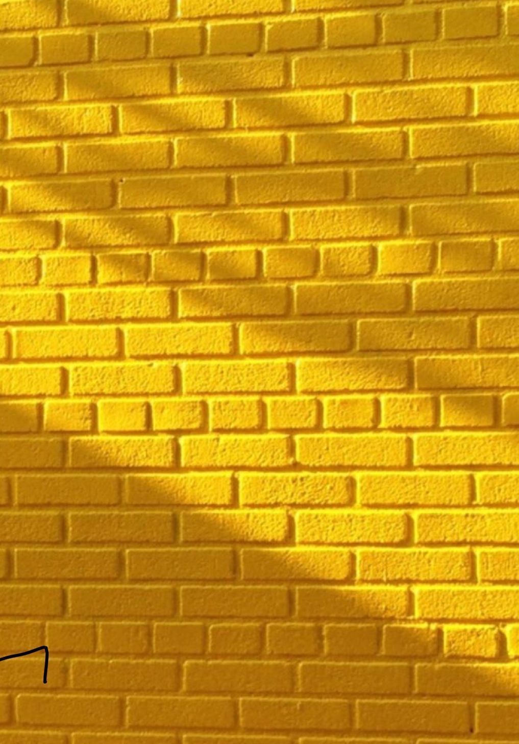 A yellow brick wall with shadows - Yellow