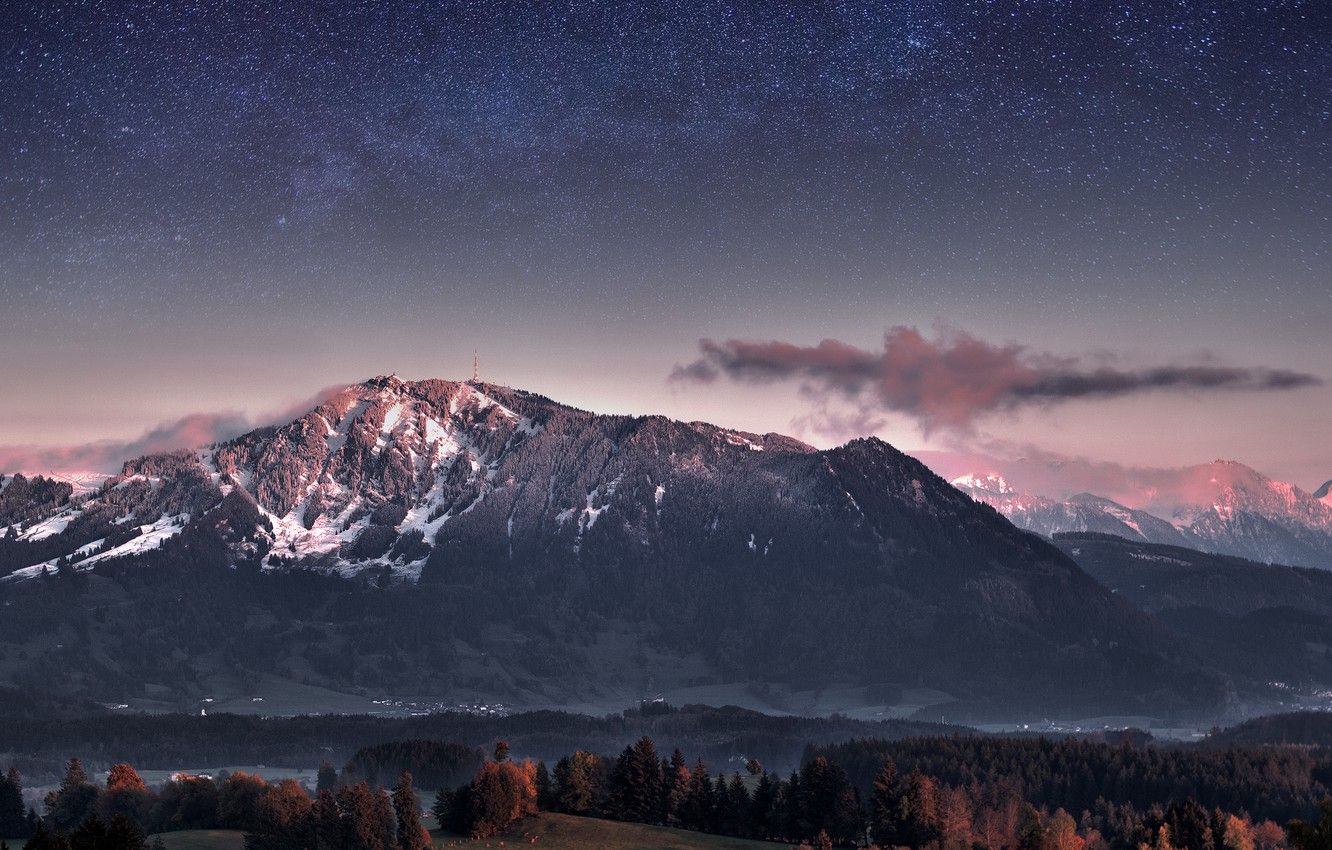 A mountain range covered in snow under a starry sky - Twilight