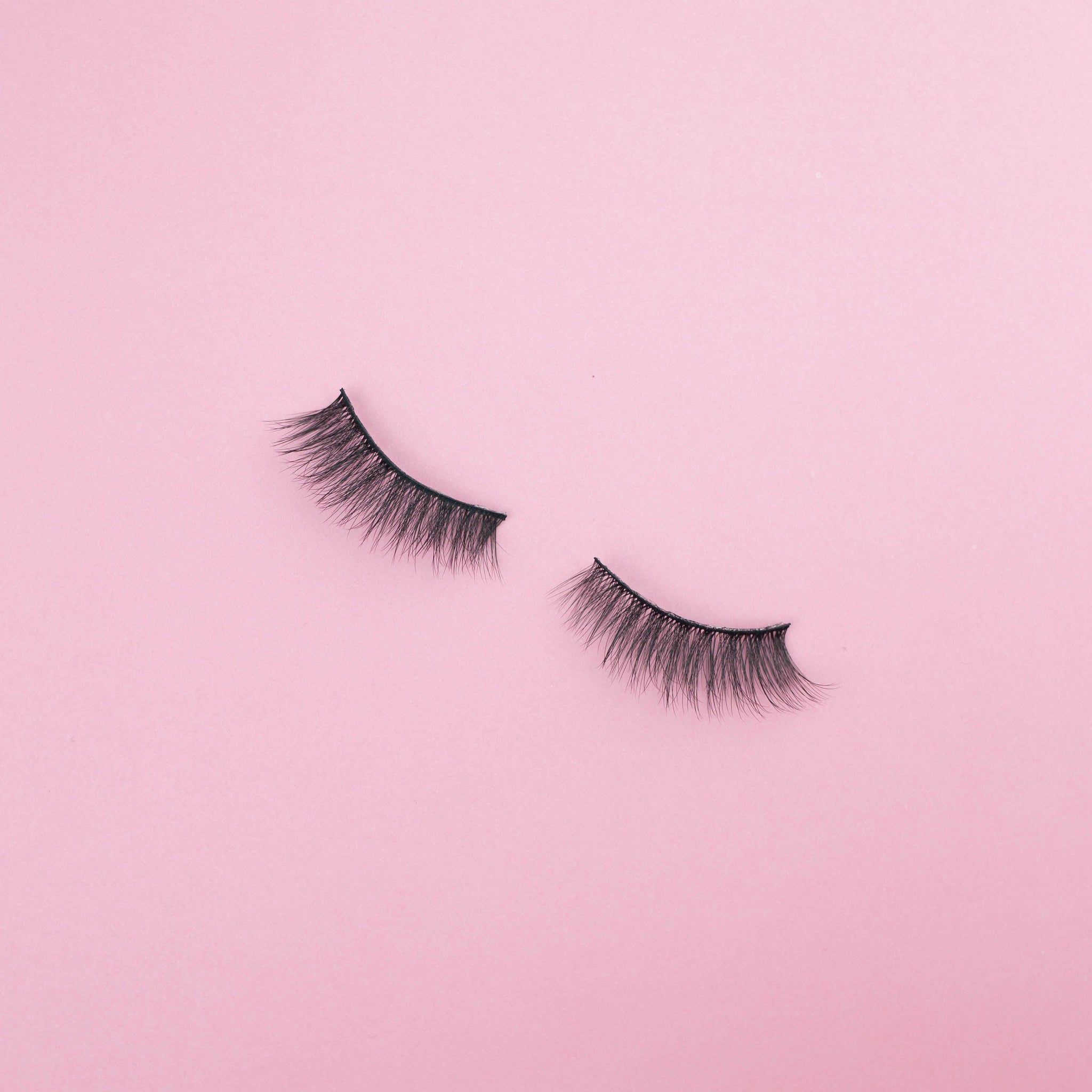 A pair of false eyelashes on a pink background. - 90s anime