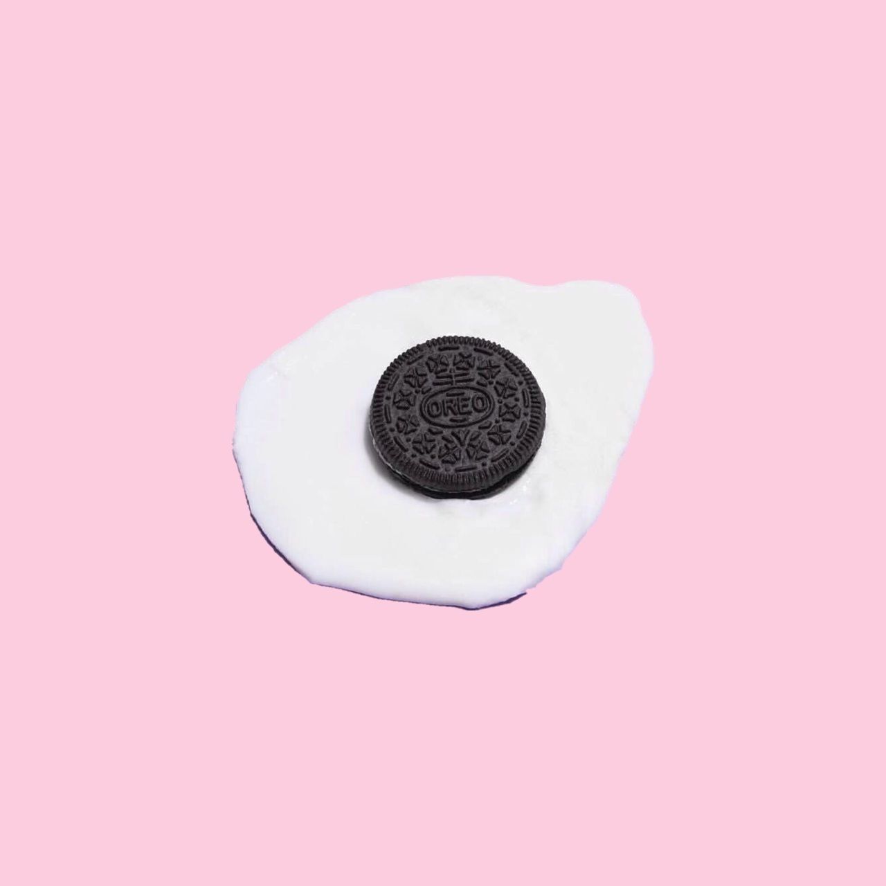 A fried egg with an Oreo in the middle on a pink background - Oreo