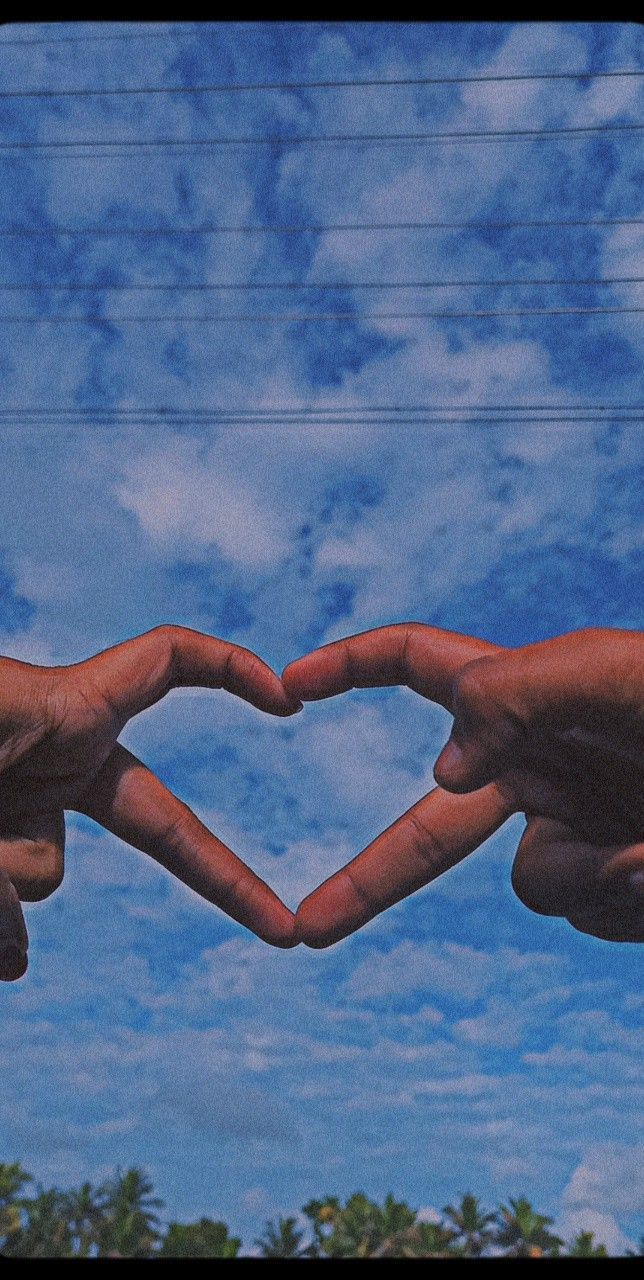 A photo of two hands forming a heart shape against a blue sky - Bestie