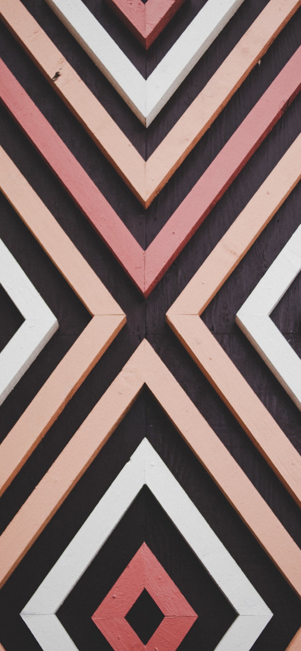 A close up of a wall with black, white, pink, and orange geometric shapes. - Pink phone