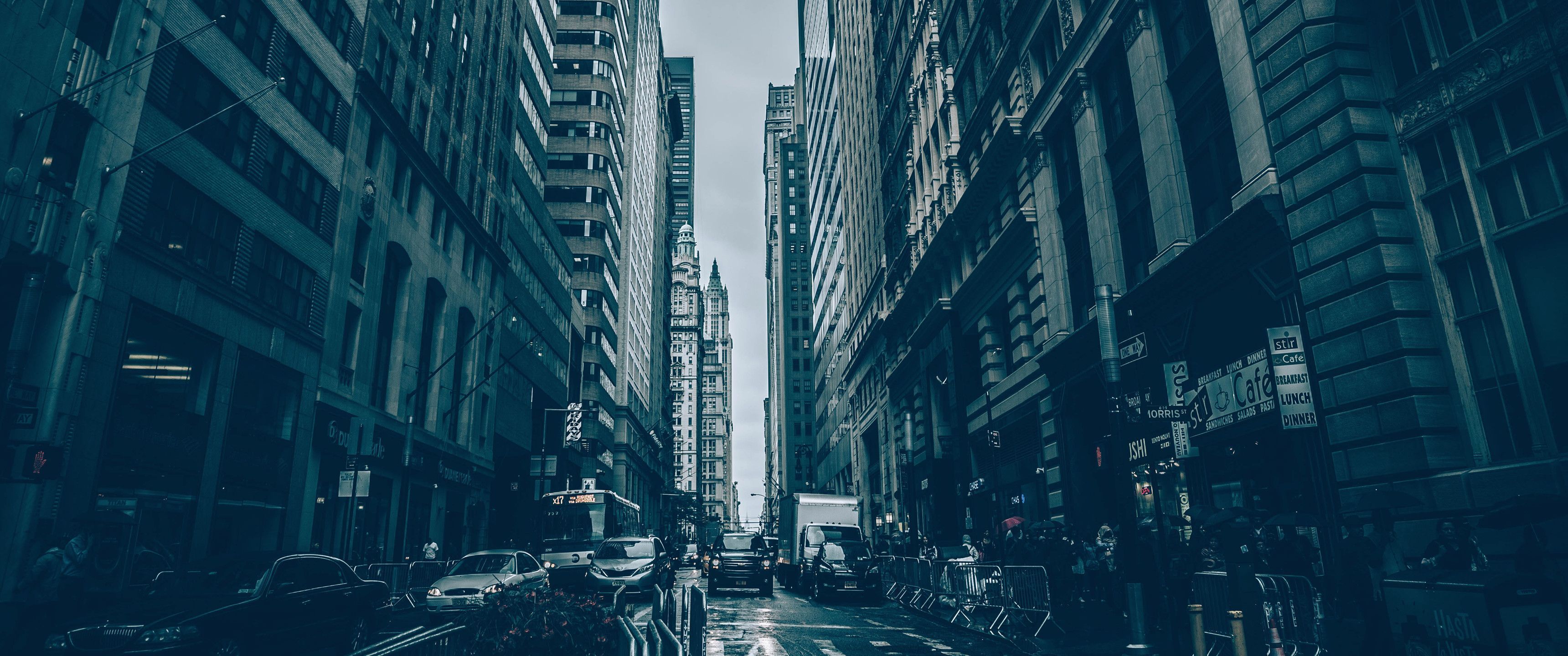 A street with tall buildings and people walking - 3440x1440