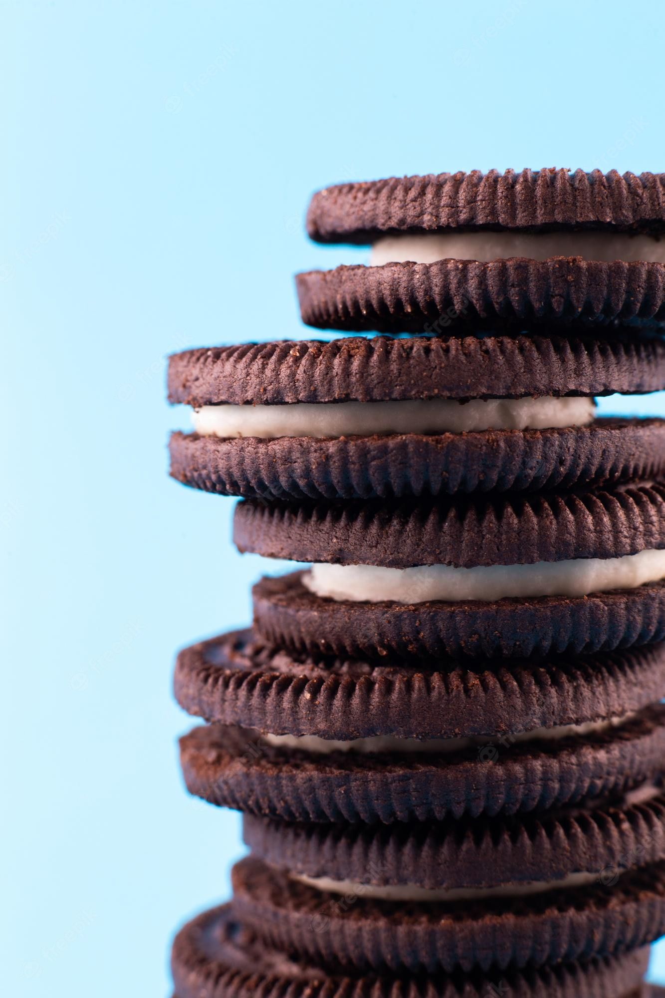 Premium Photo. Macro chocolate cookies and white cream isolated on blue backgroundxa