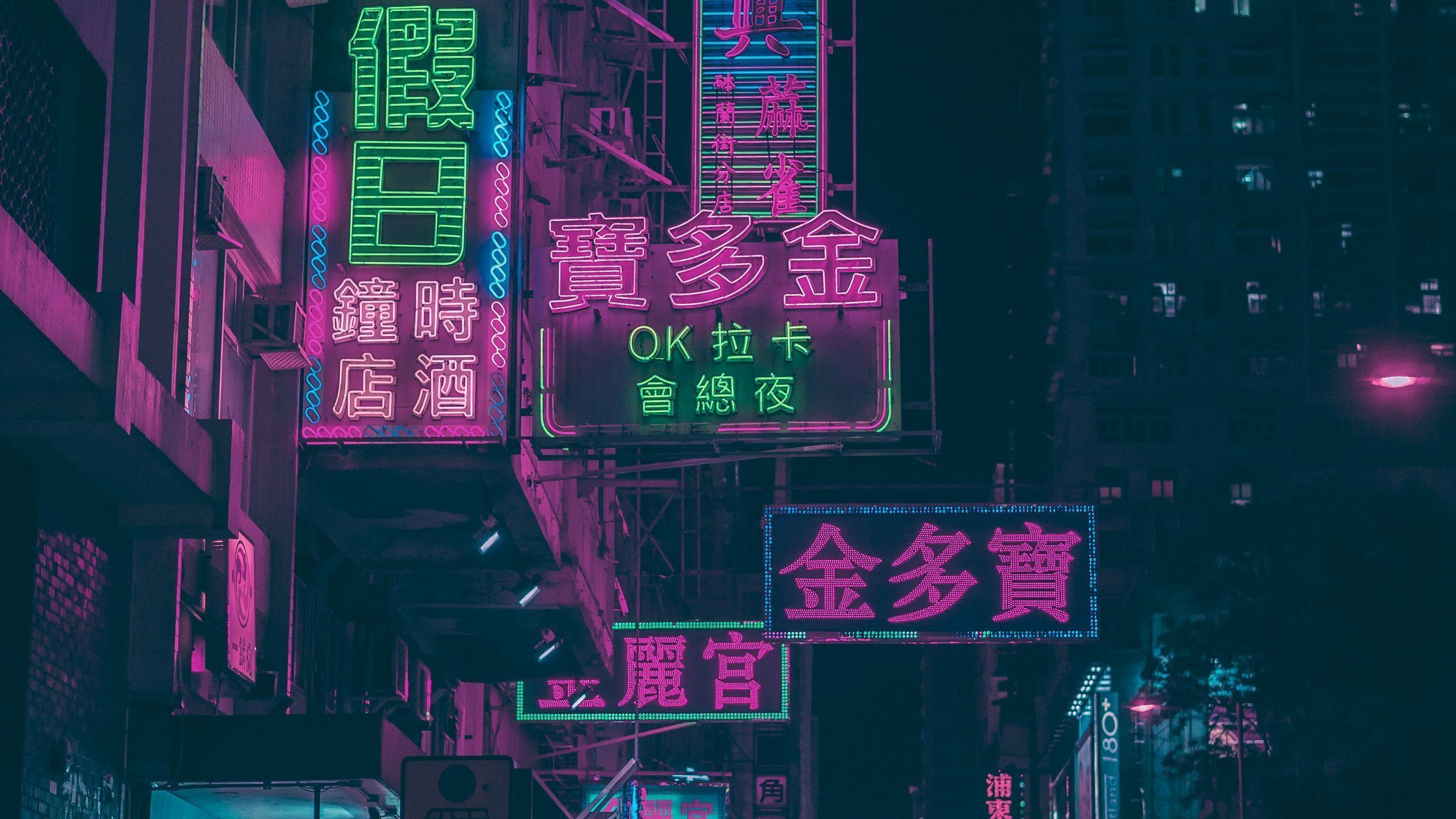 A street at night with neon signs in pink and green. - 2560x1440