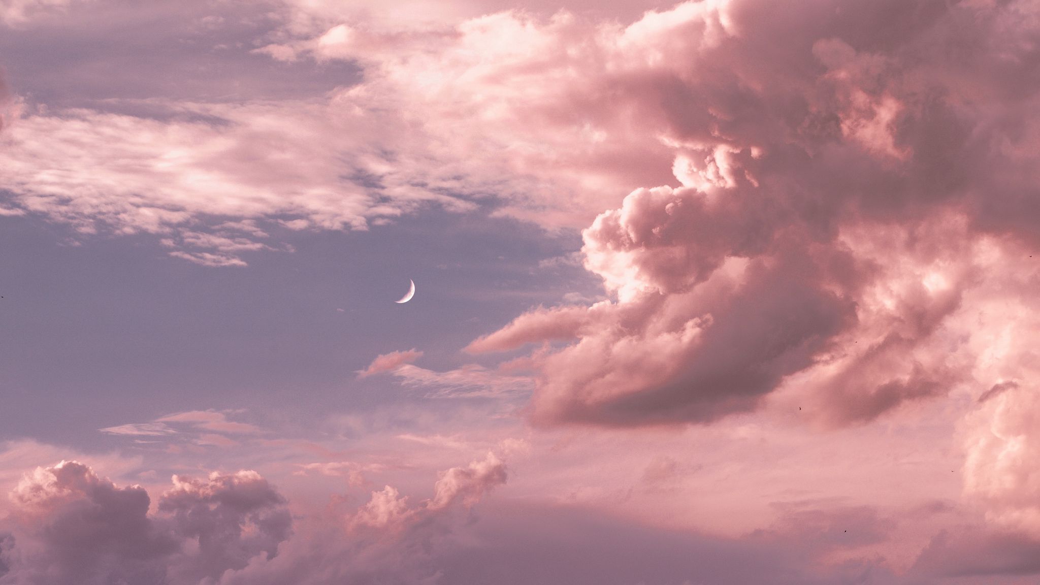 A pink and purple sky with a crescent moon peaking through the clouds. - 2048x1152