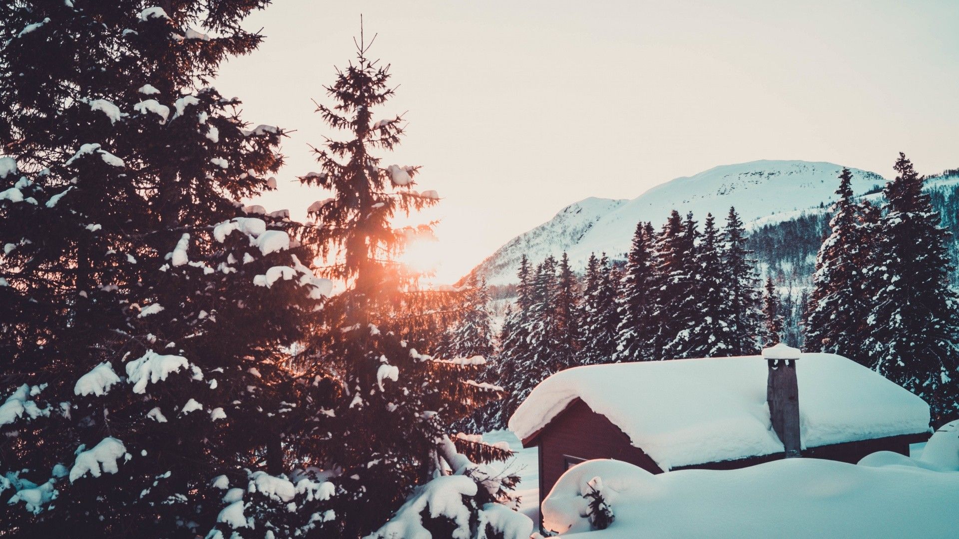 A cabin in the snow with the sun setting behind it - Landscape
